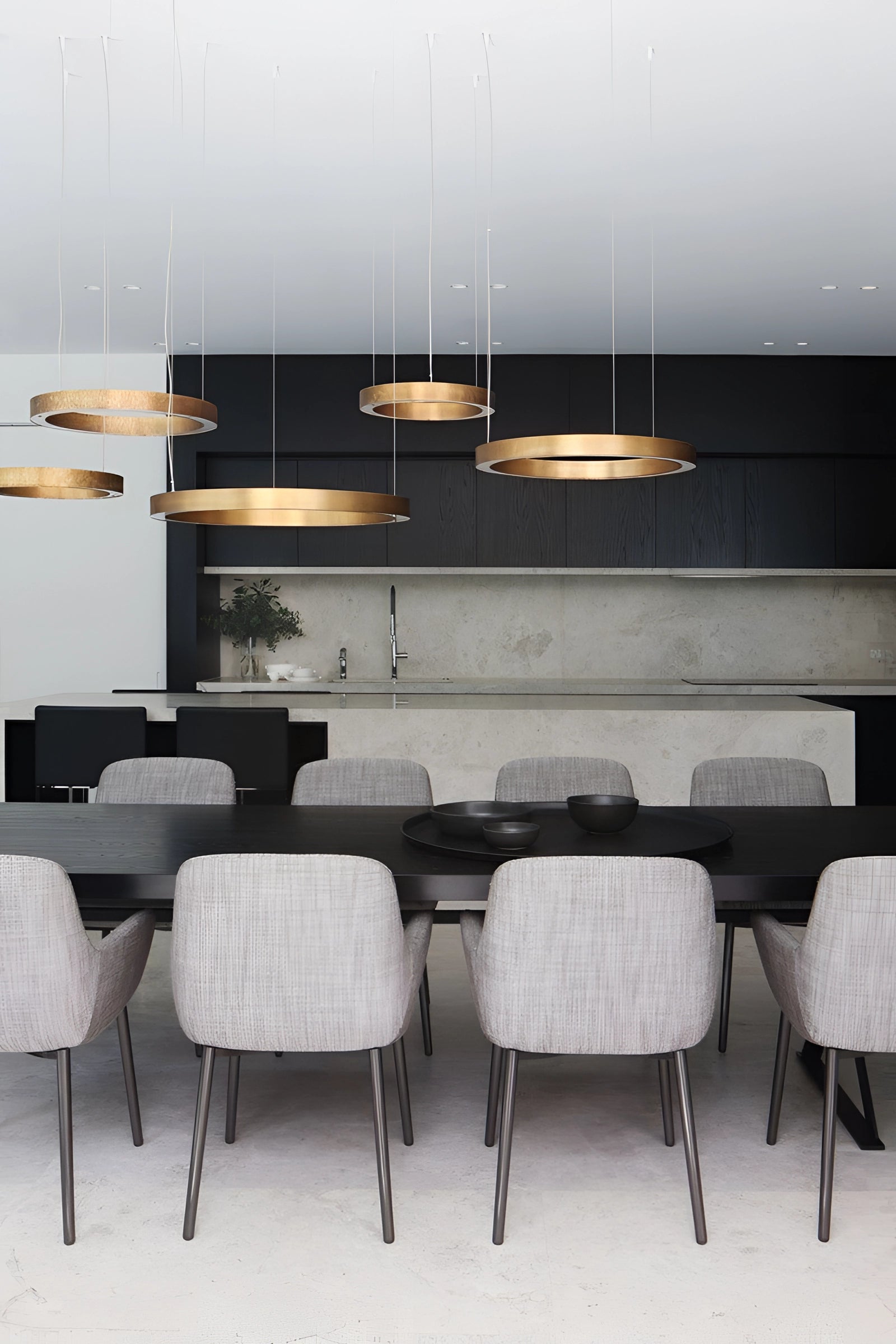 Modern circular LED ring pendant light hanging in a luxury hotel lobby, showcasing elegant interior design with grey and wood elements including furniture and cabinetry.