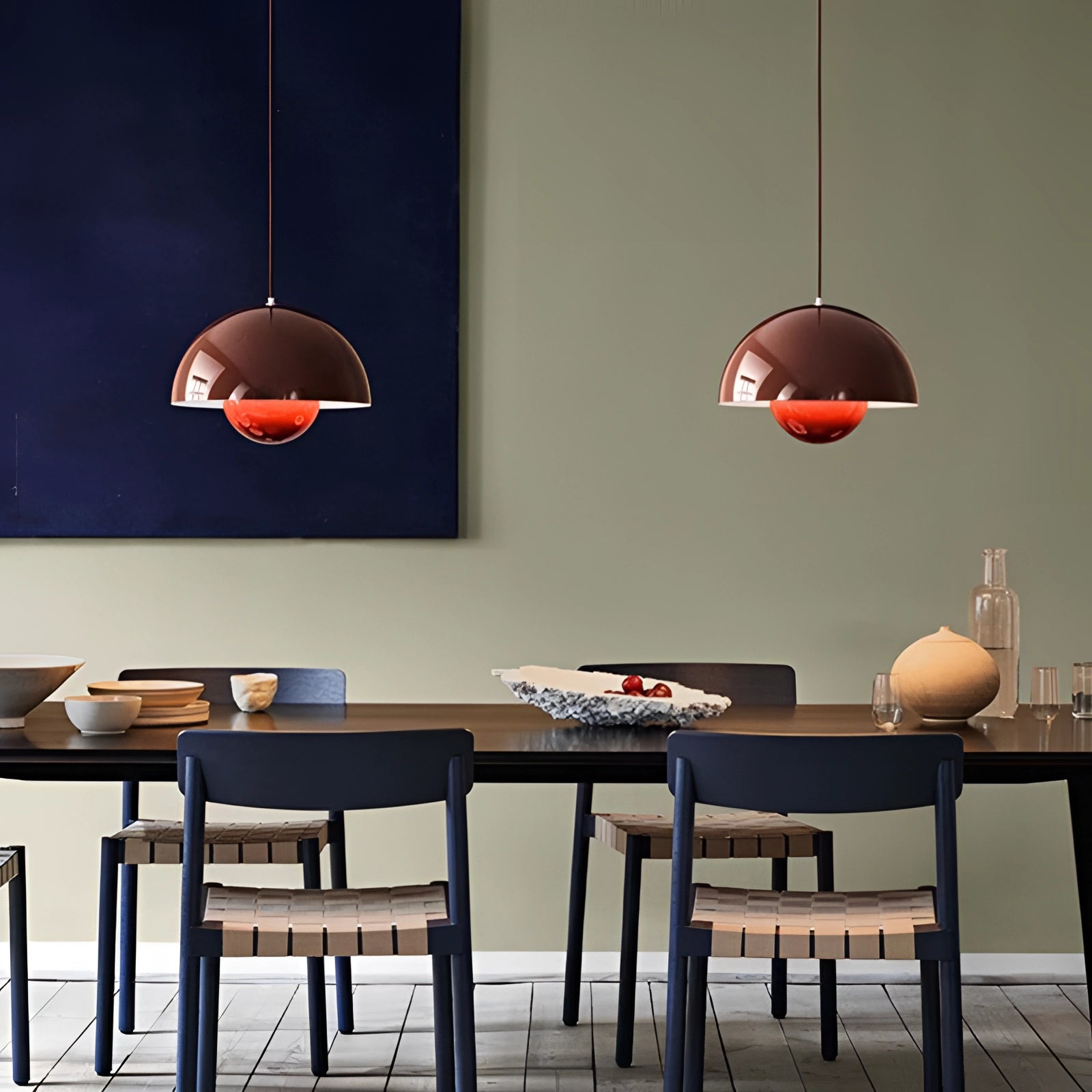 Modern copper pendant light with a Scandinavian minimalist design hanging above a wooden table, illuminating an interior space with warm orange lighting.