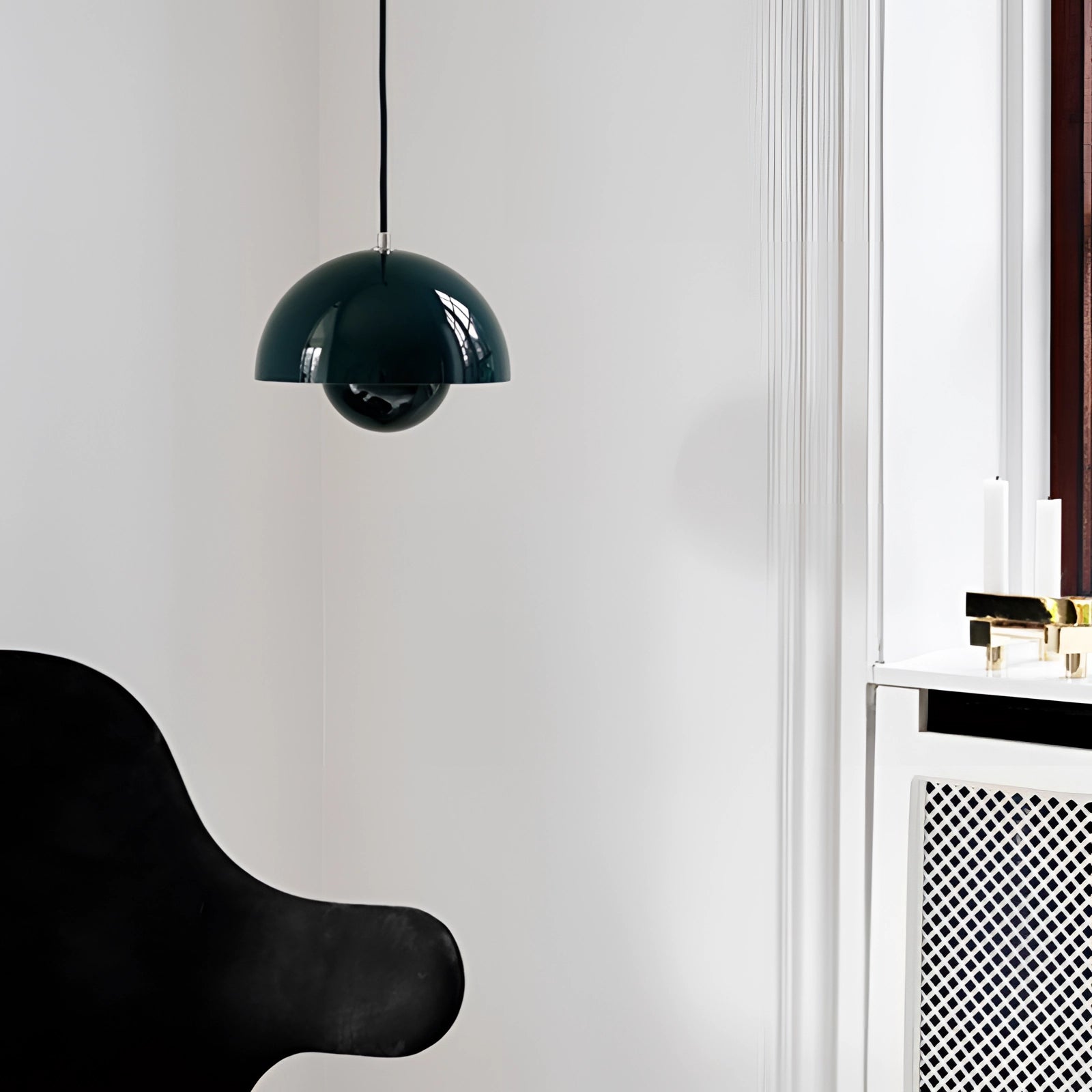 Modern copper pendant light with Scandinavian minimalist design, featuring a dark green finish, hanging from the ceiling in a room. The fixture has a sleek, circular shape and complements the monochrome and wooden elements of the space.