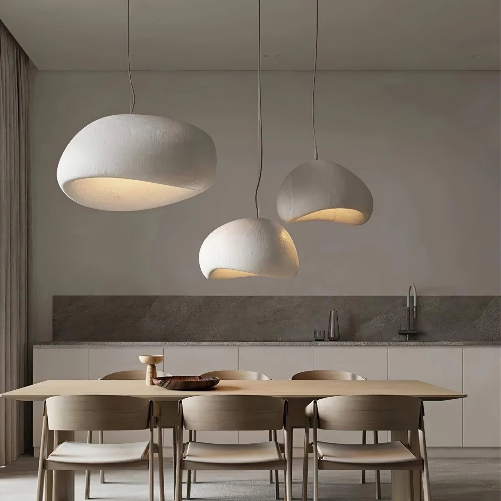 Modern curved pendant light with a minimalist sculptural design, hanging above a wooden table in a contemporary interior setting.