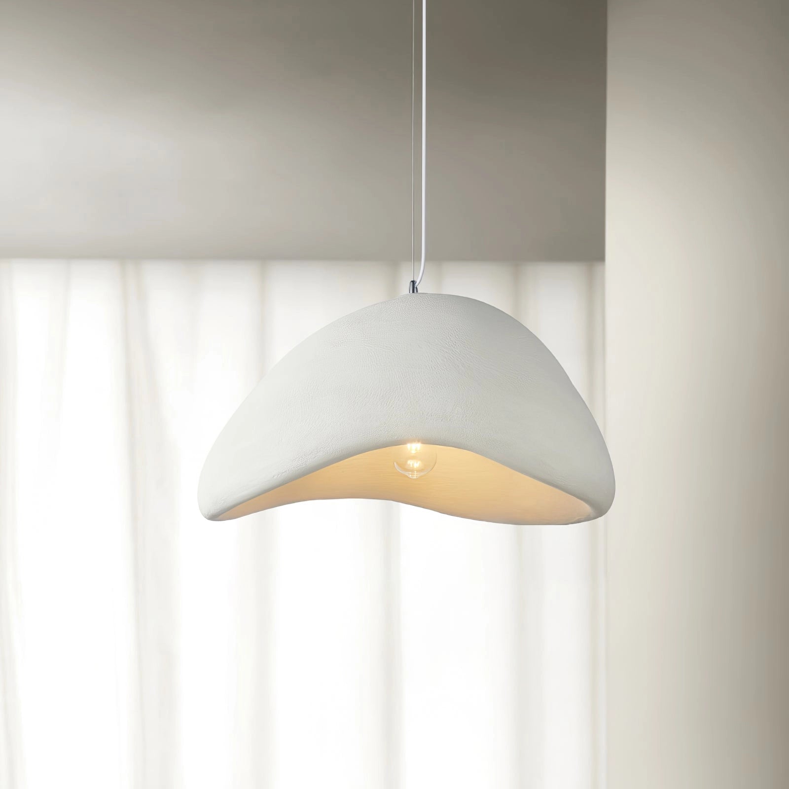 Modern curved pendant light with a minimalist design featuring a sculptural lampshade made of wood and metal, suspended from the ceiling as a stylish ceiling fixture.