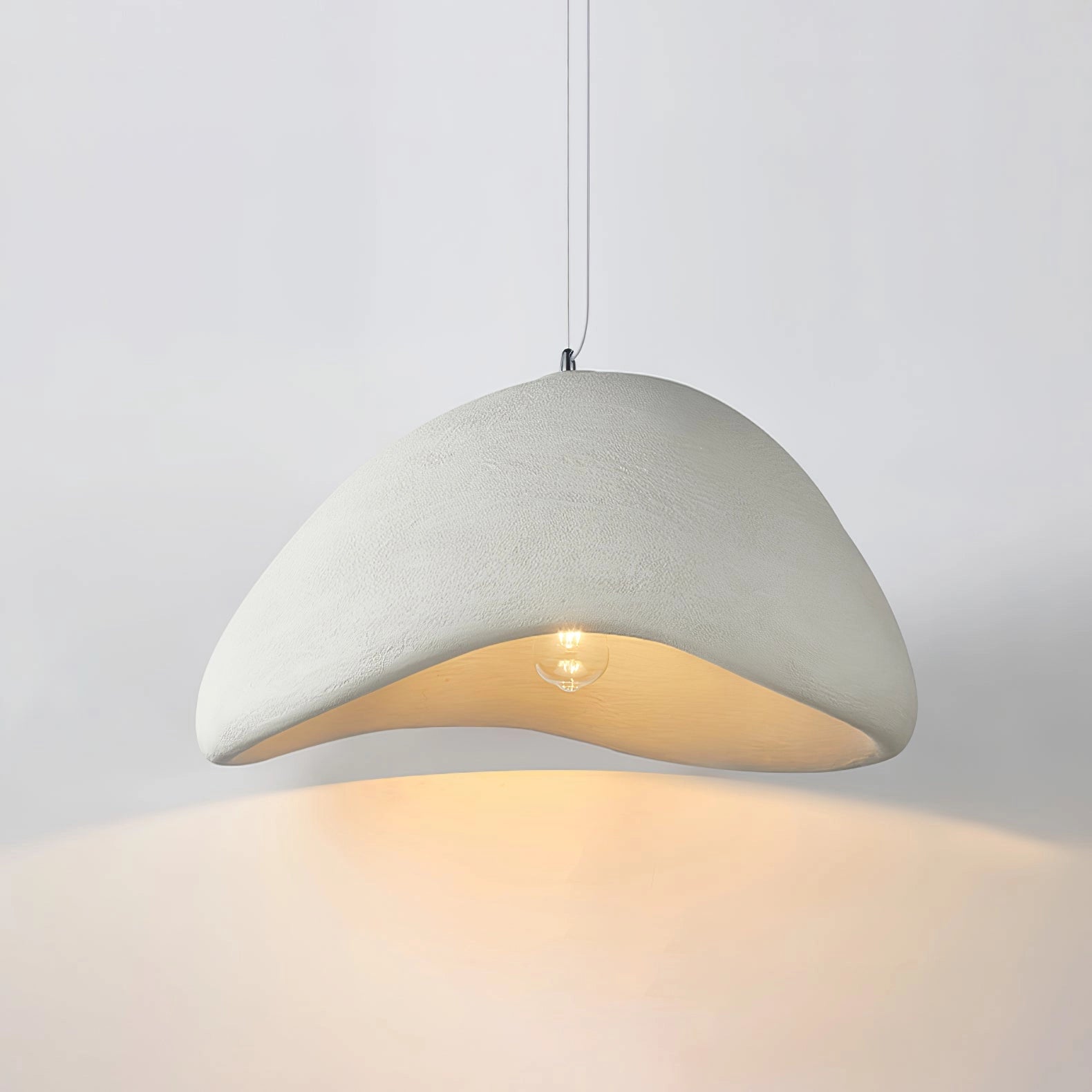 Modern curved pendant light with a minimalist sculptural design, featuring a sleek metal finish and suspended from the ceiling. The elegant lampshade casts soft tints and shades, adding sophistication to any room.