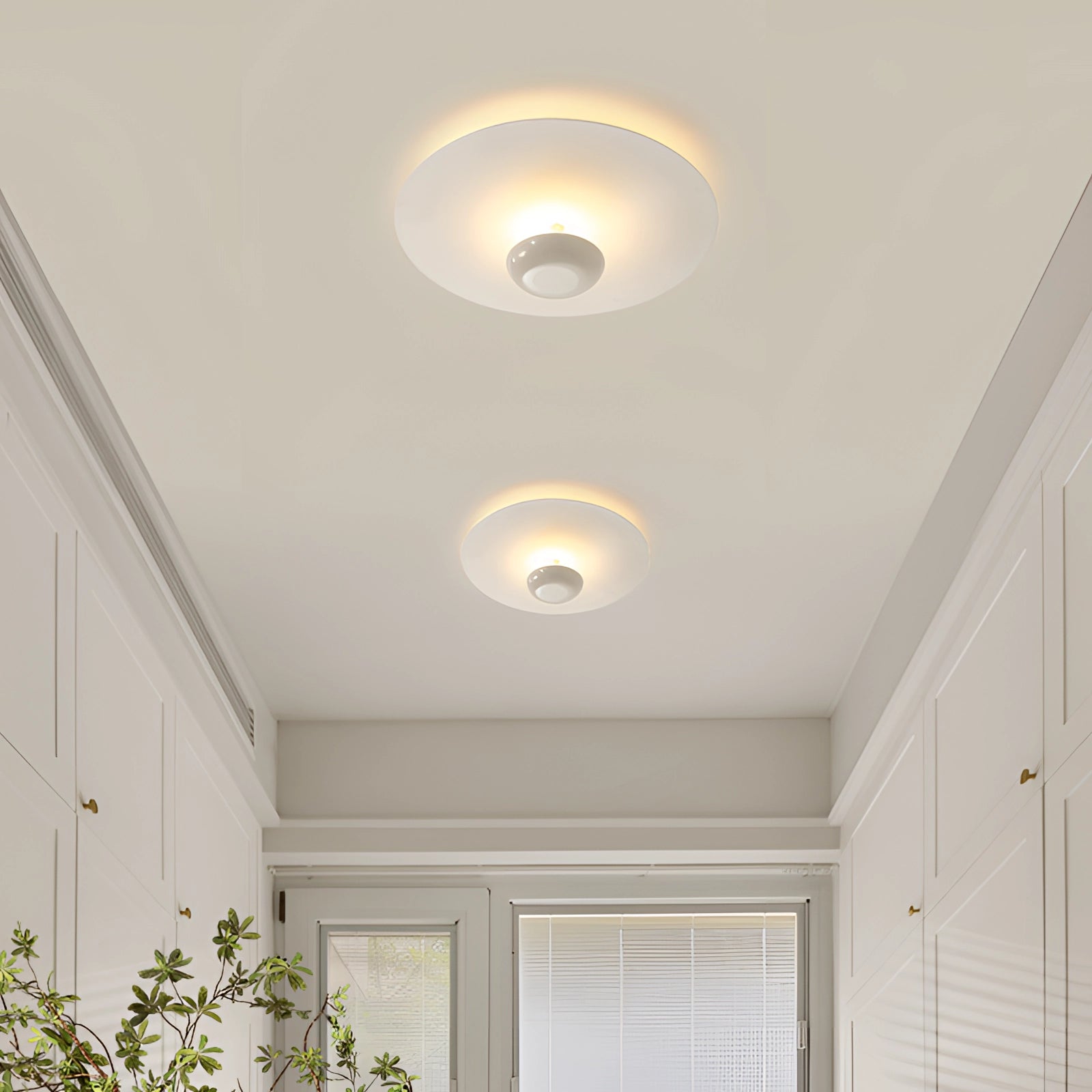 Modern flush mount ceiling light with a round, minimalist design featuring a white and chrome finish, mounted on a ceiling, blending with the surrounding building materials.