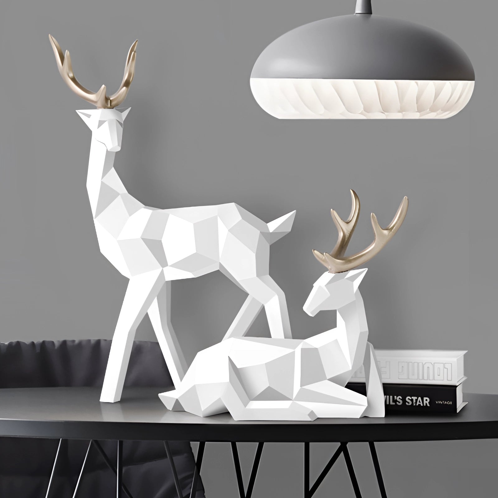 White geometric deer sculpture with a minimalist design, featuring clean lines and angles. Displayed against a light-colored wall, the sculpture resembles a stylized deer or fawn, making it a striking piece of modern art decor.