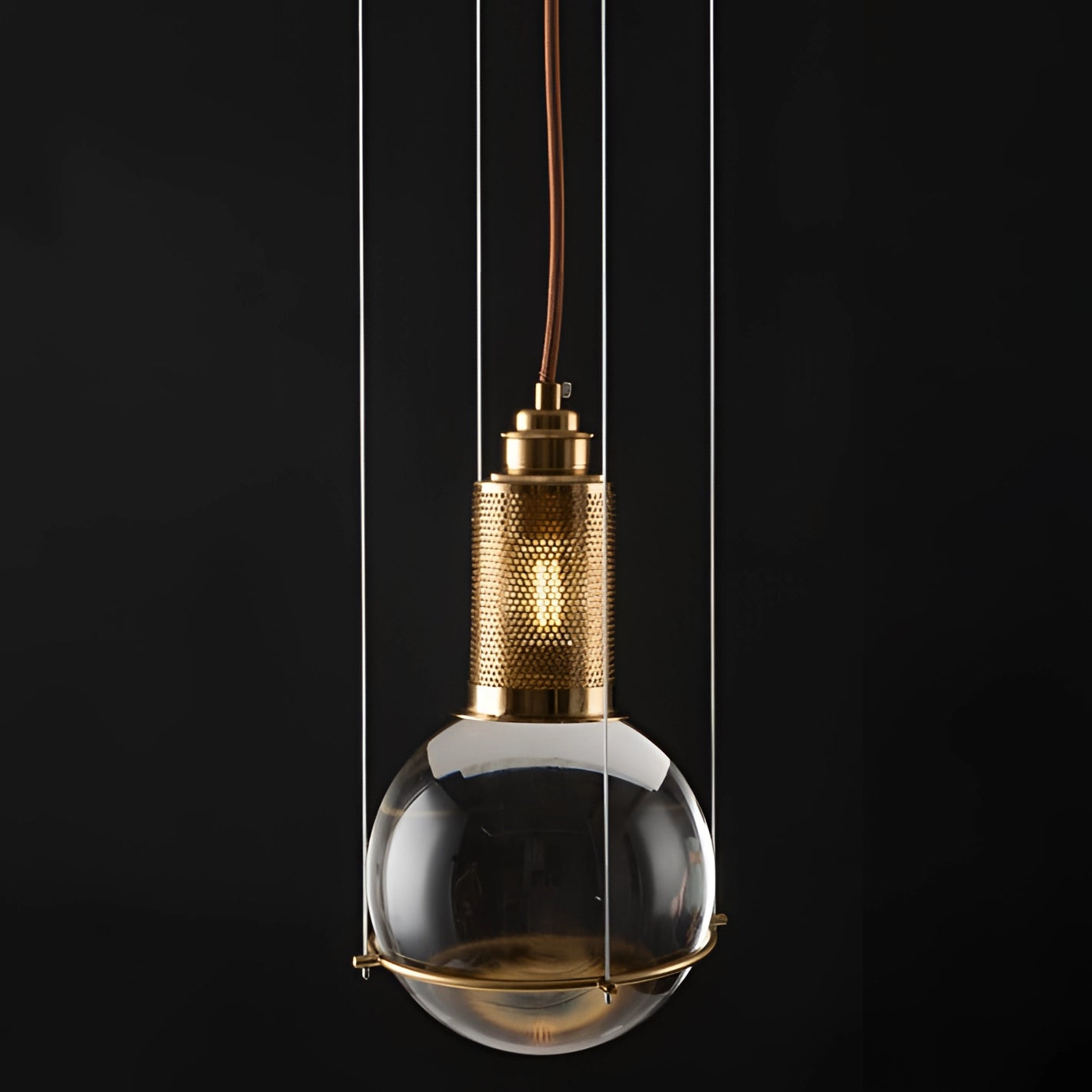 Modern glass globe pendant light with gold accents, featuring a minimalist design. The pendant is suspended from the ceiling, showcasing a spherical glass globe and metal fixtures.