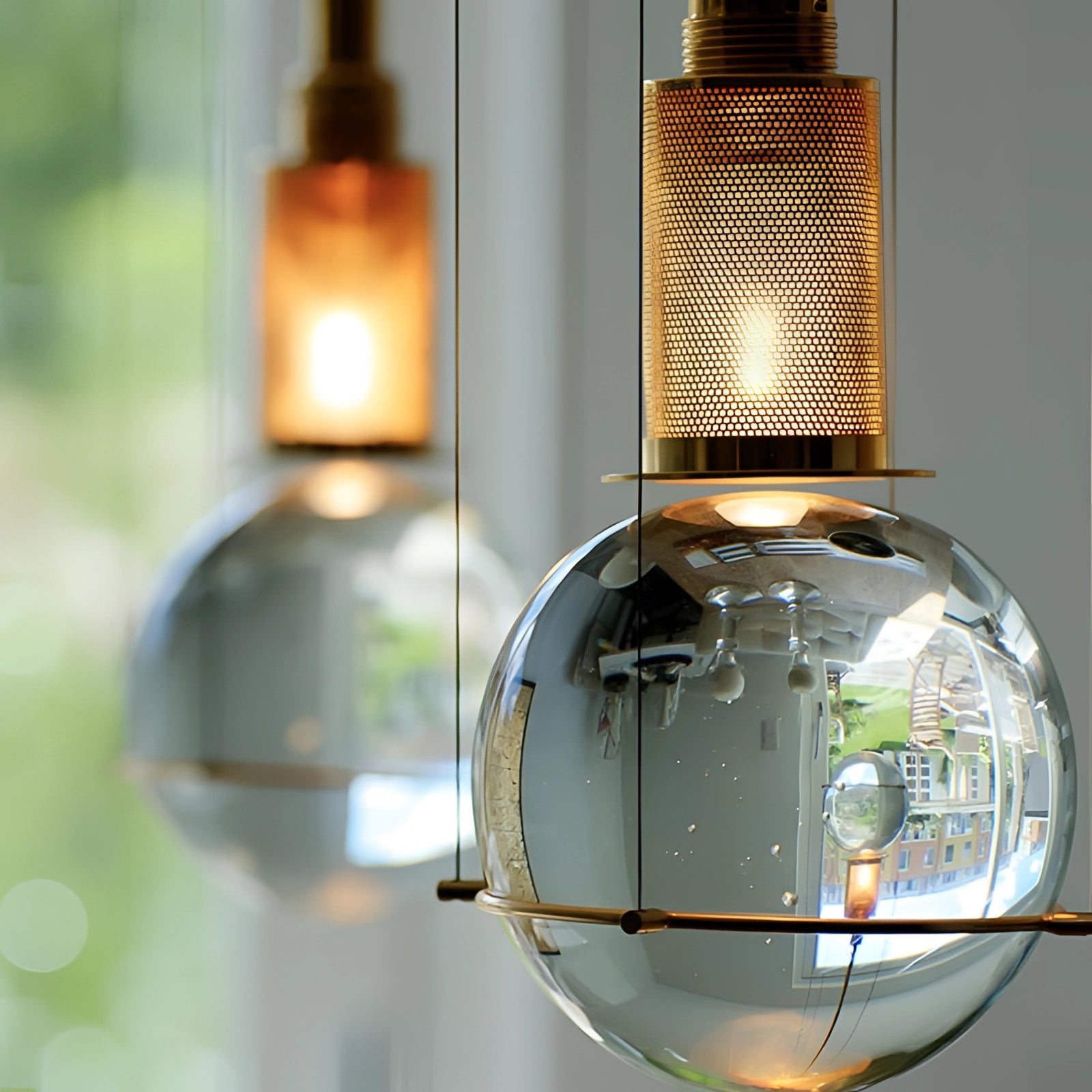 Modern glass globe pendant light with a gold finish, featuring a minimalist design and transparent glass shade, showcasing a designer lighting fixture with an elegant and contemporary aesthetic.