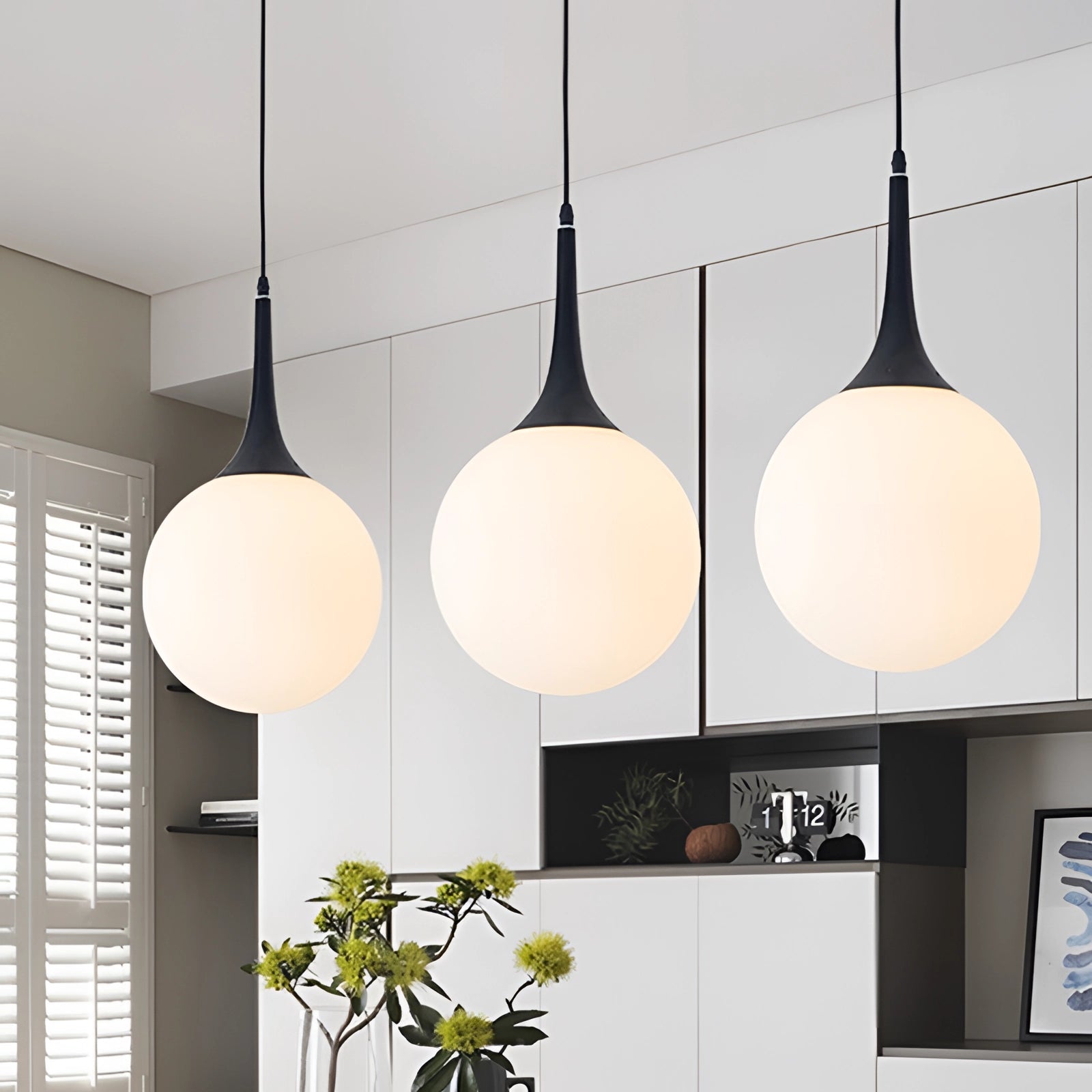 Modern globe pendant light with black and white glass hanging from ceiling in a stylish interior, surrounded by plants and contemporary decor elements.