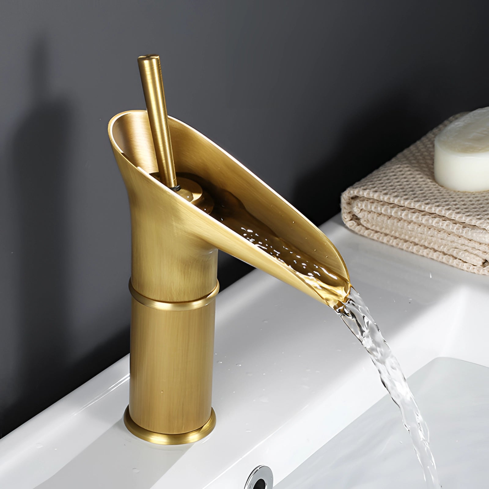 A modern gold waterfall faucet with a luxury brass finish designed for a vessel sink.