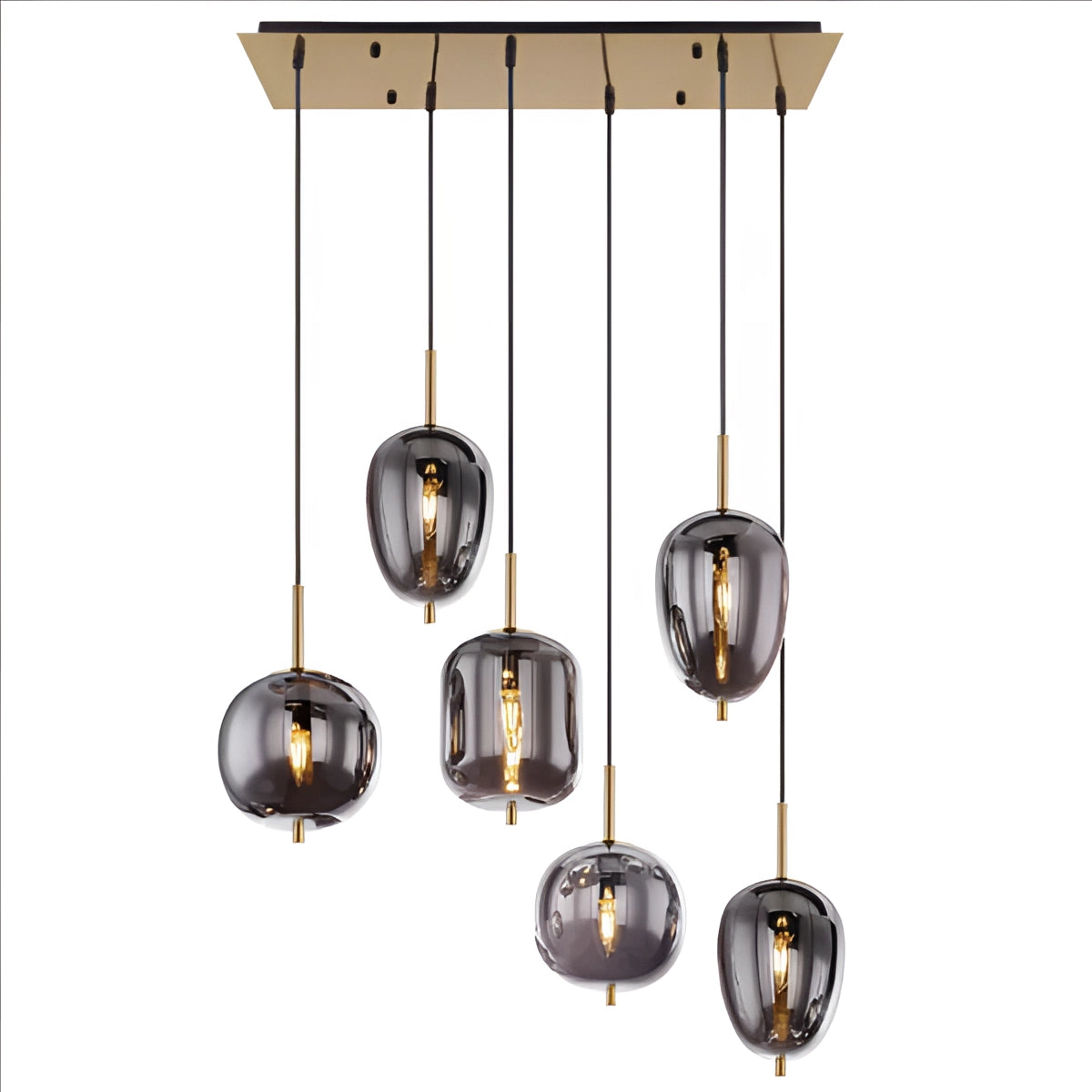 Modern industrial glass pendant lights with a bronze finish and six smoke gray heads featuring brass accents, hanging above a wooden dining table with plants and shelving in the background.