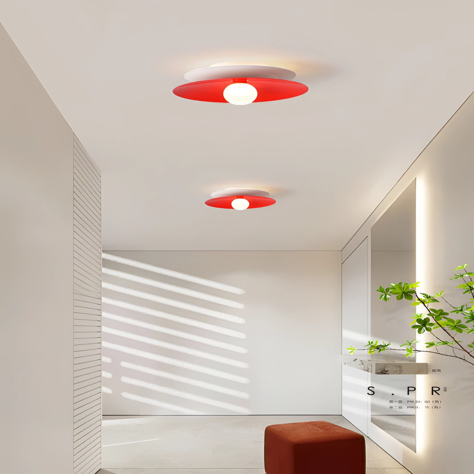 Modern minimalist LED disc ceiling light fixture in red with warm white illumination, mounted on a ceiling in a stylish interior setting with wooden elements and cabinetry.