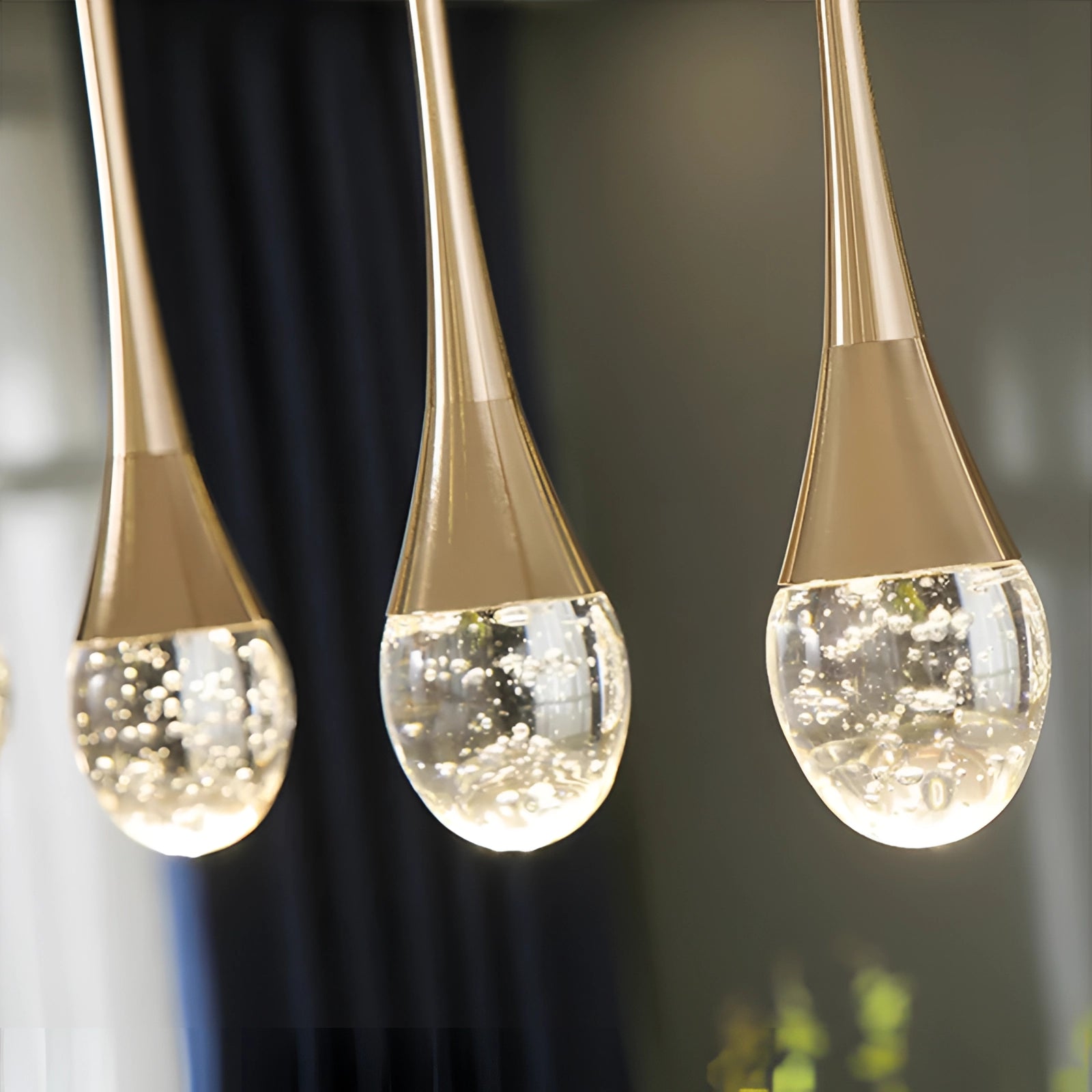 Modern LED gold teardrop pendant light with a sleek glass and metal design, suitable for kitchens and dining rooms.