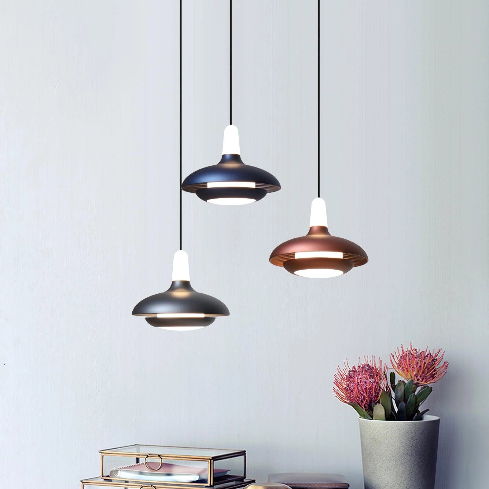 Modern LED pendant light with a sleek, minimalistic design featuring an adjustable cord, hanging above a wooden surface with a houseplant in a flowerpot. The light illuminates the area with soft tints and shades, creating a stylish and contemporary ambiance.