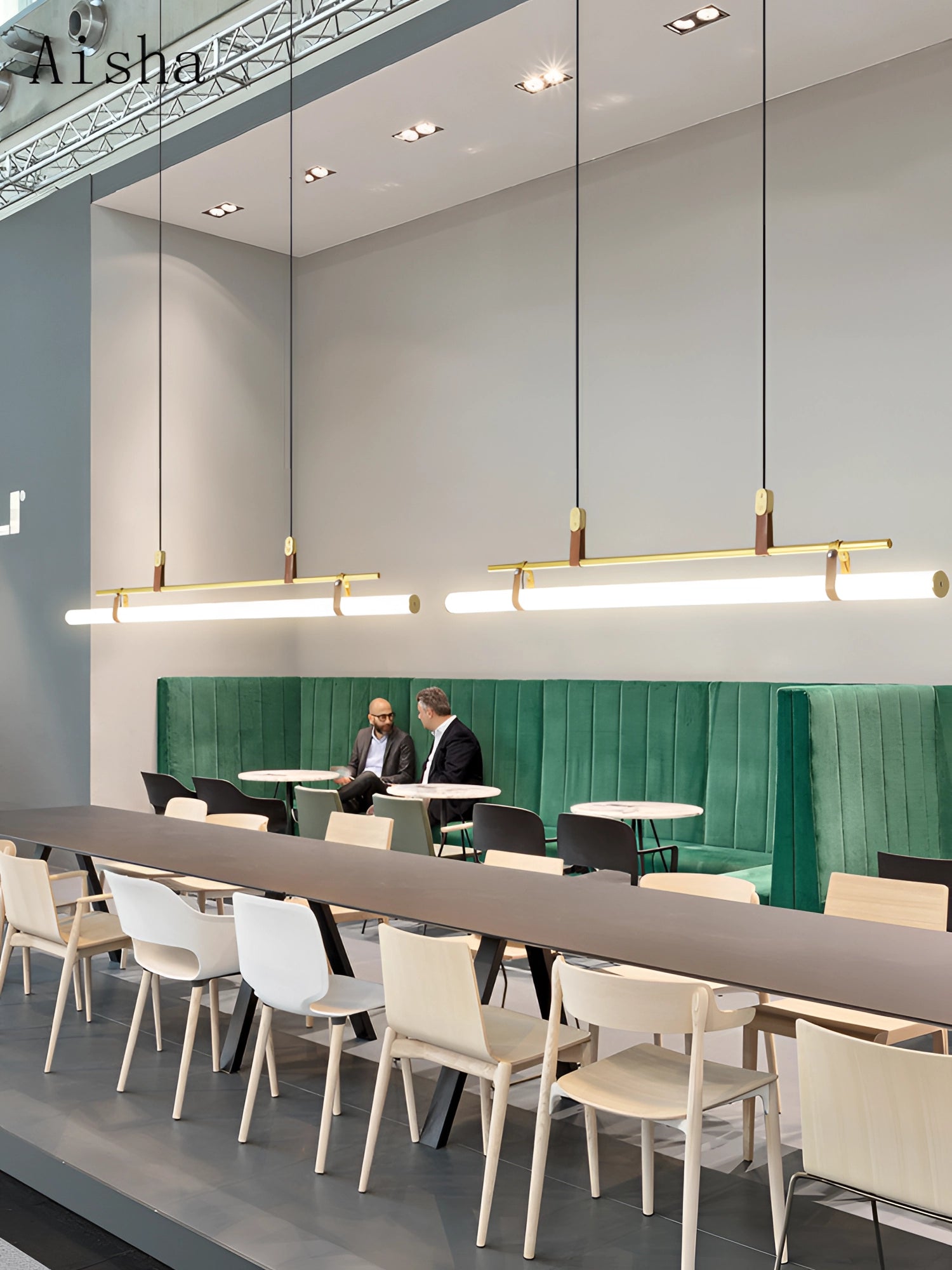 Modern LED tube pendant light hanging from the ceiling above a minimalist kitchen and dining room setting, featuring a sleek table and chairs on polished flooring.