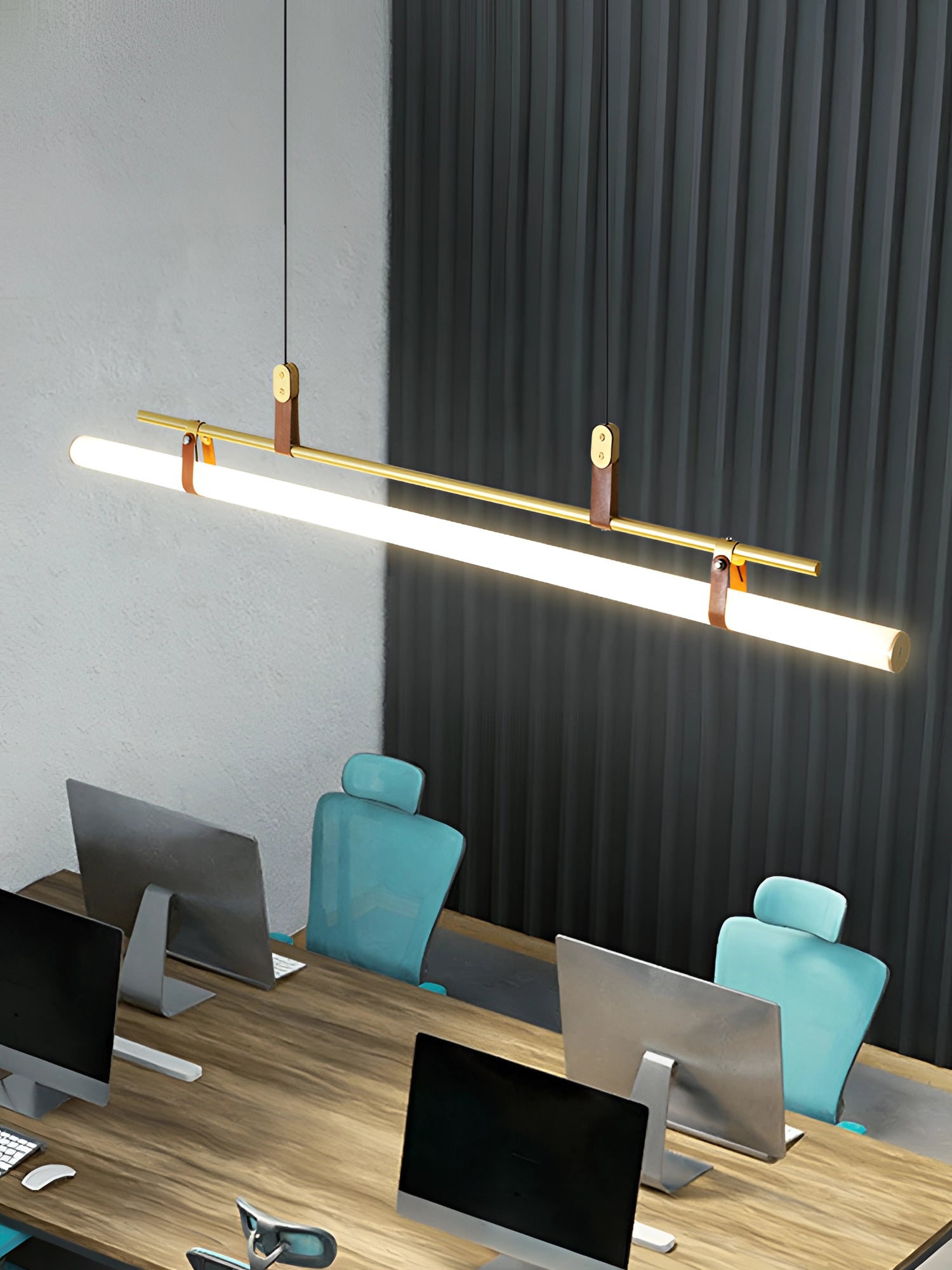 Modern LED tube pendant light hanging above a minimalist kitchen and dining room setting with wooden flooring, a table, and a couch in the background.