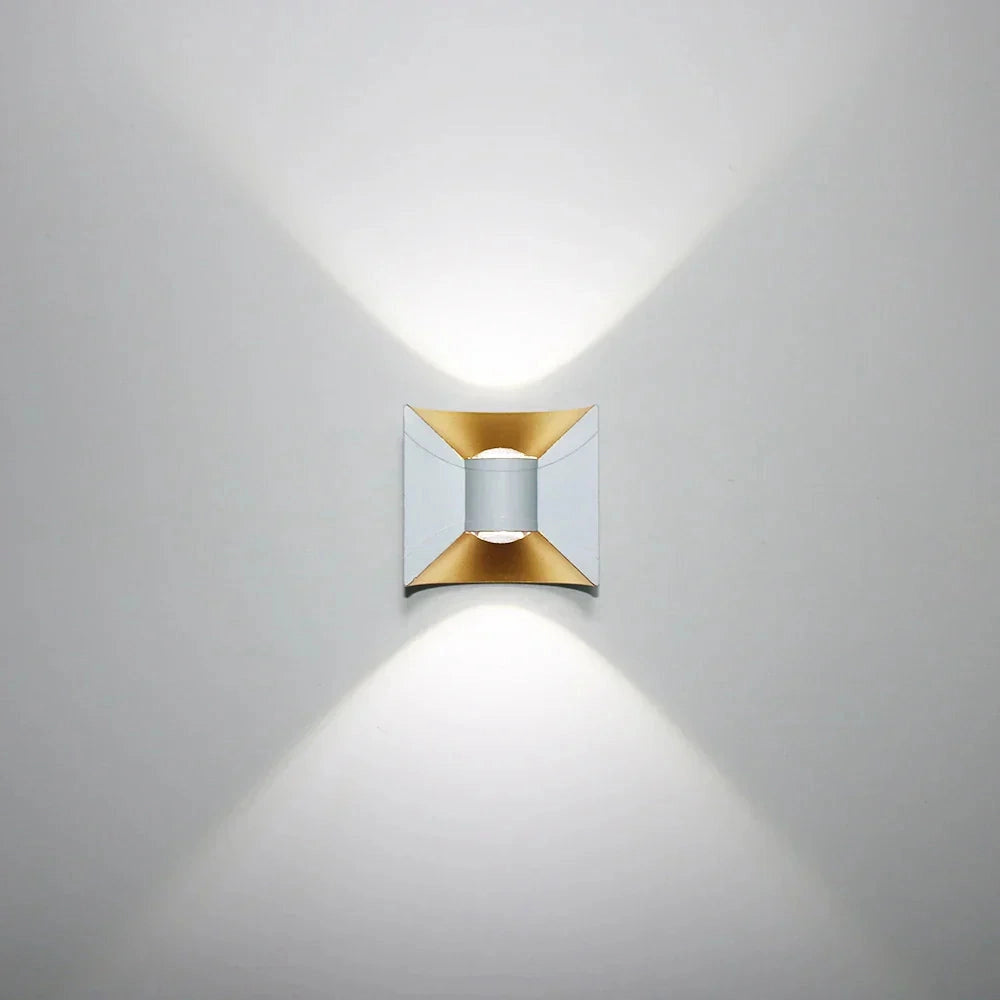 Modern LED wall sconce with a black and gold geometric design featuring a white and cool white lighting option, showcasing a combination of circular and rectangular shapes, mounted on a wall.