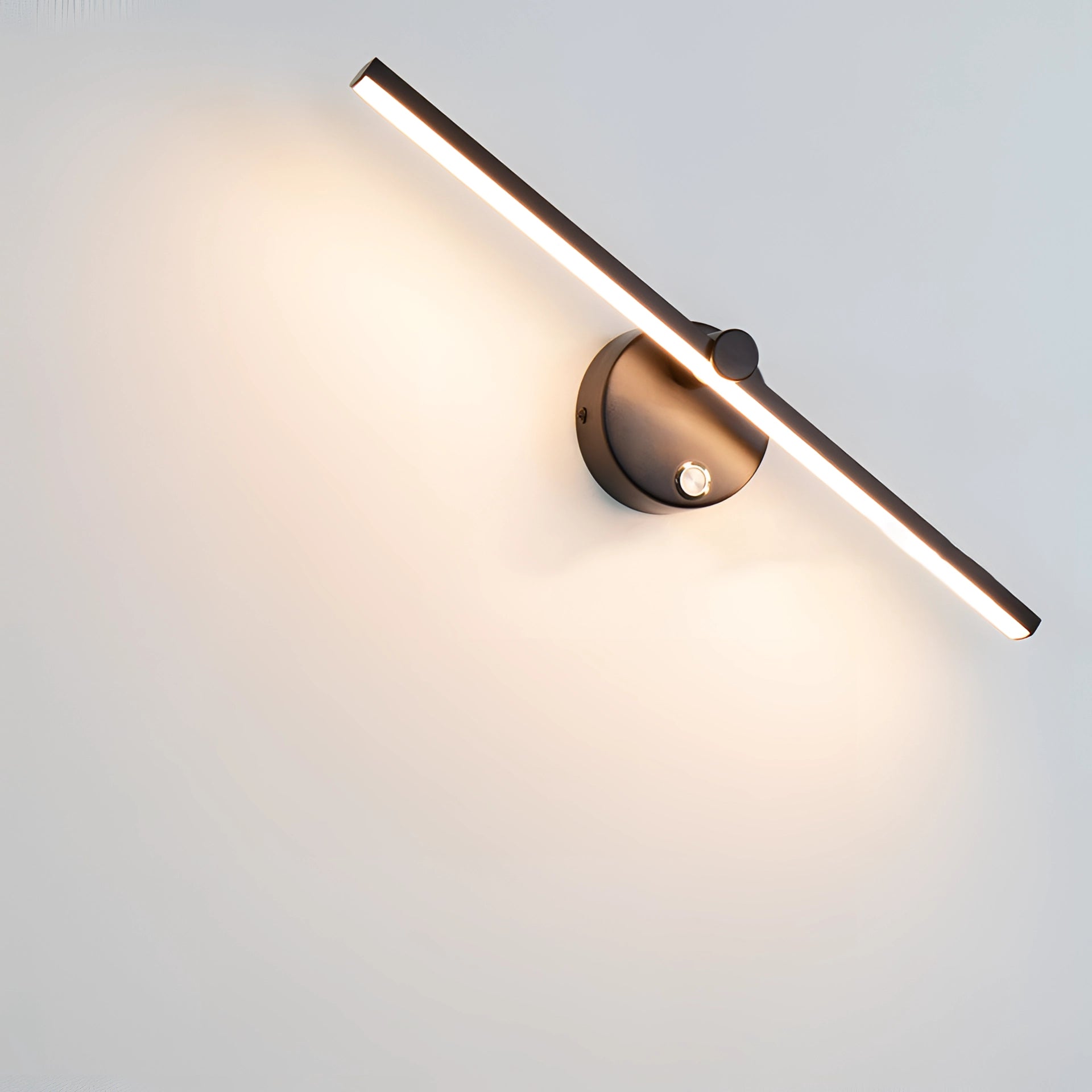 Modern LED wall sconce in black, featuring a brushed gold finish, mounted on a wall with a switch. The sconce emits neutral light (4000K) and is compatible with 110 V-120 V power for USA/Canada. The image includes a wooden wall and door with a metal handle in a room with office supplies and a ceiling clock.