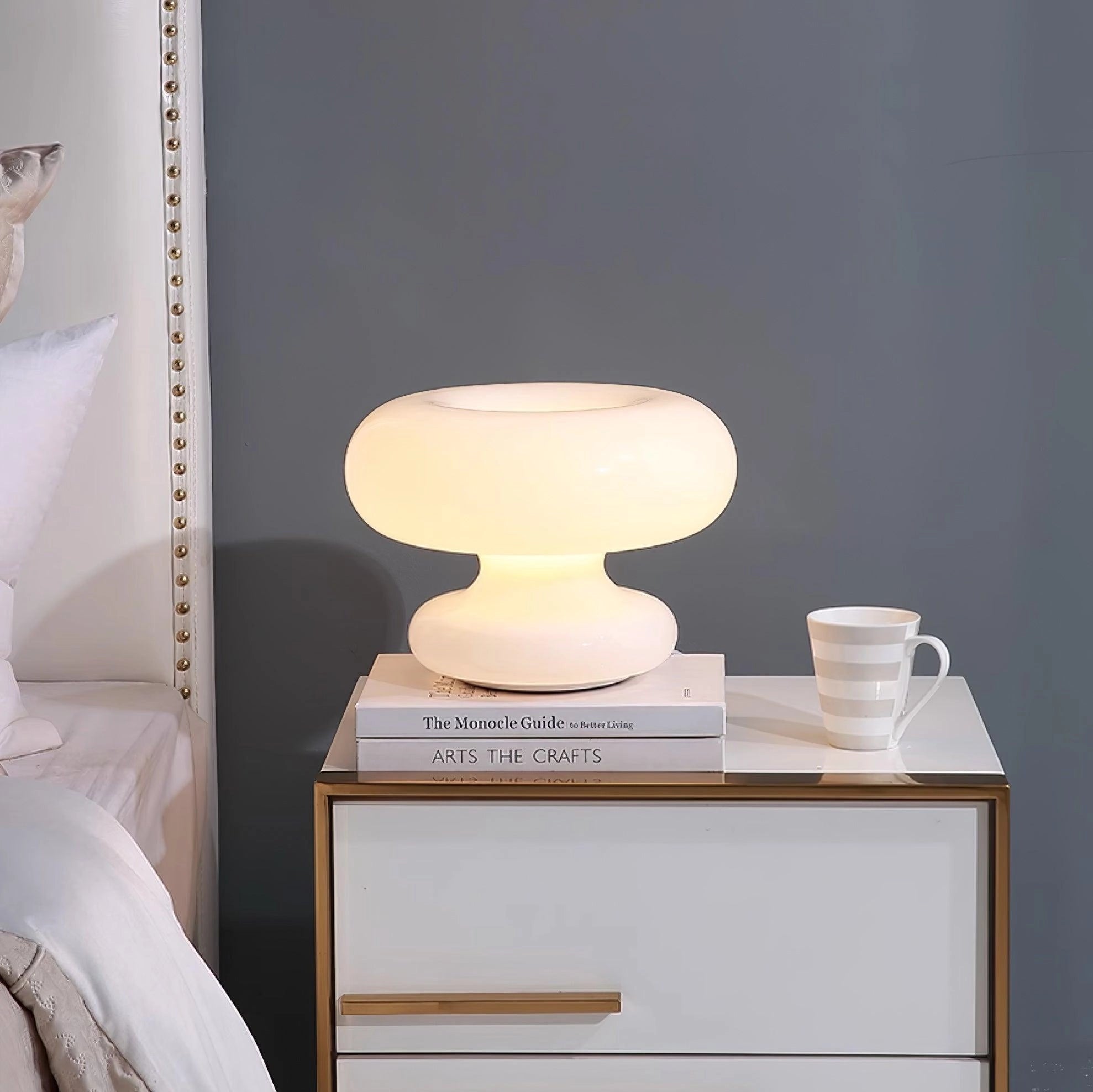 Modern mushroom-shaped table lamp with a minimalist design, featuring a wooden base and positioned on a bedside table.