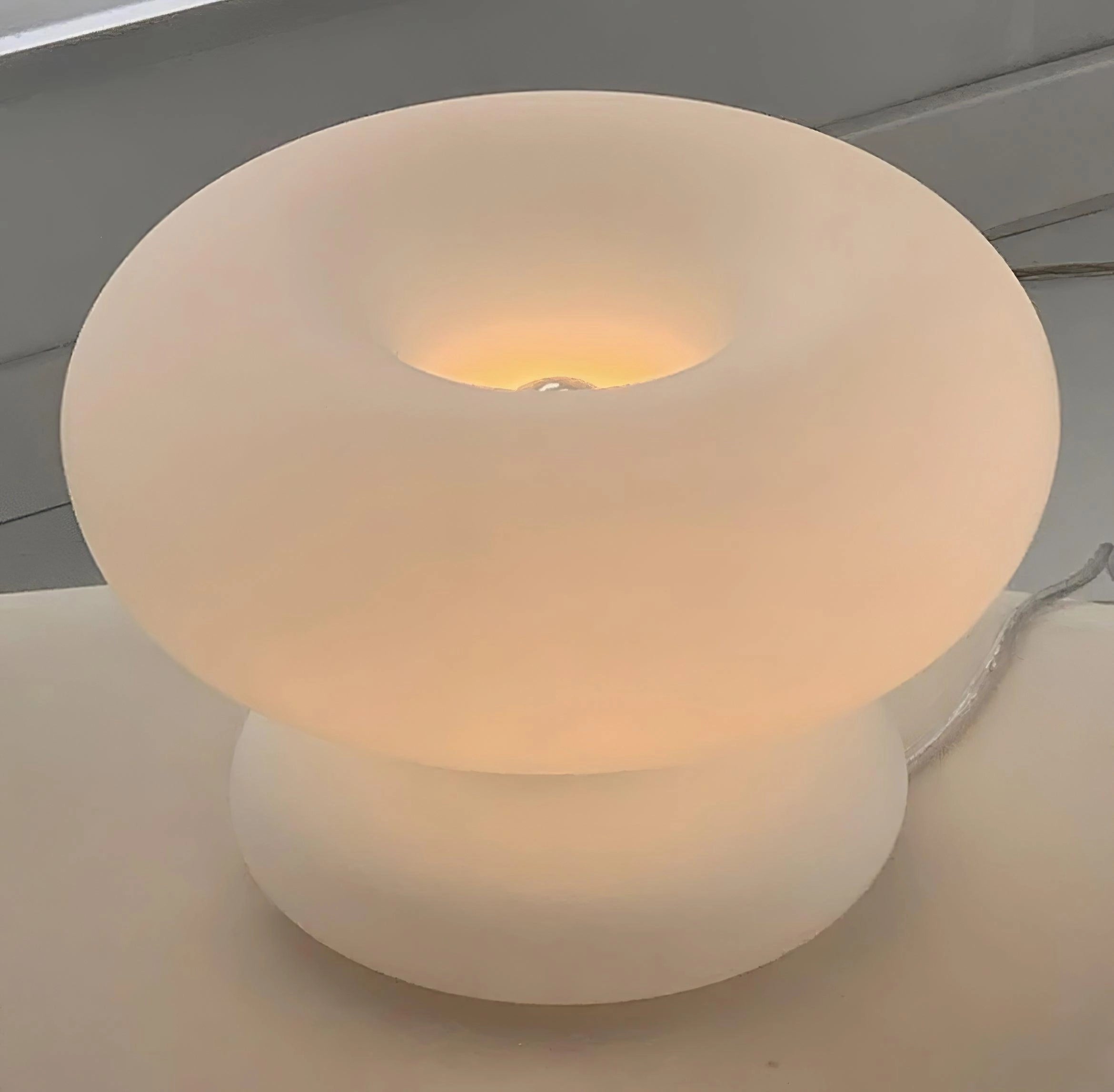 A modern mushroom-shaped table lamp with a minimalist design, featuring a smooth, circular base and a soft, diffused light, perfect for bedside illumination.