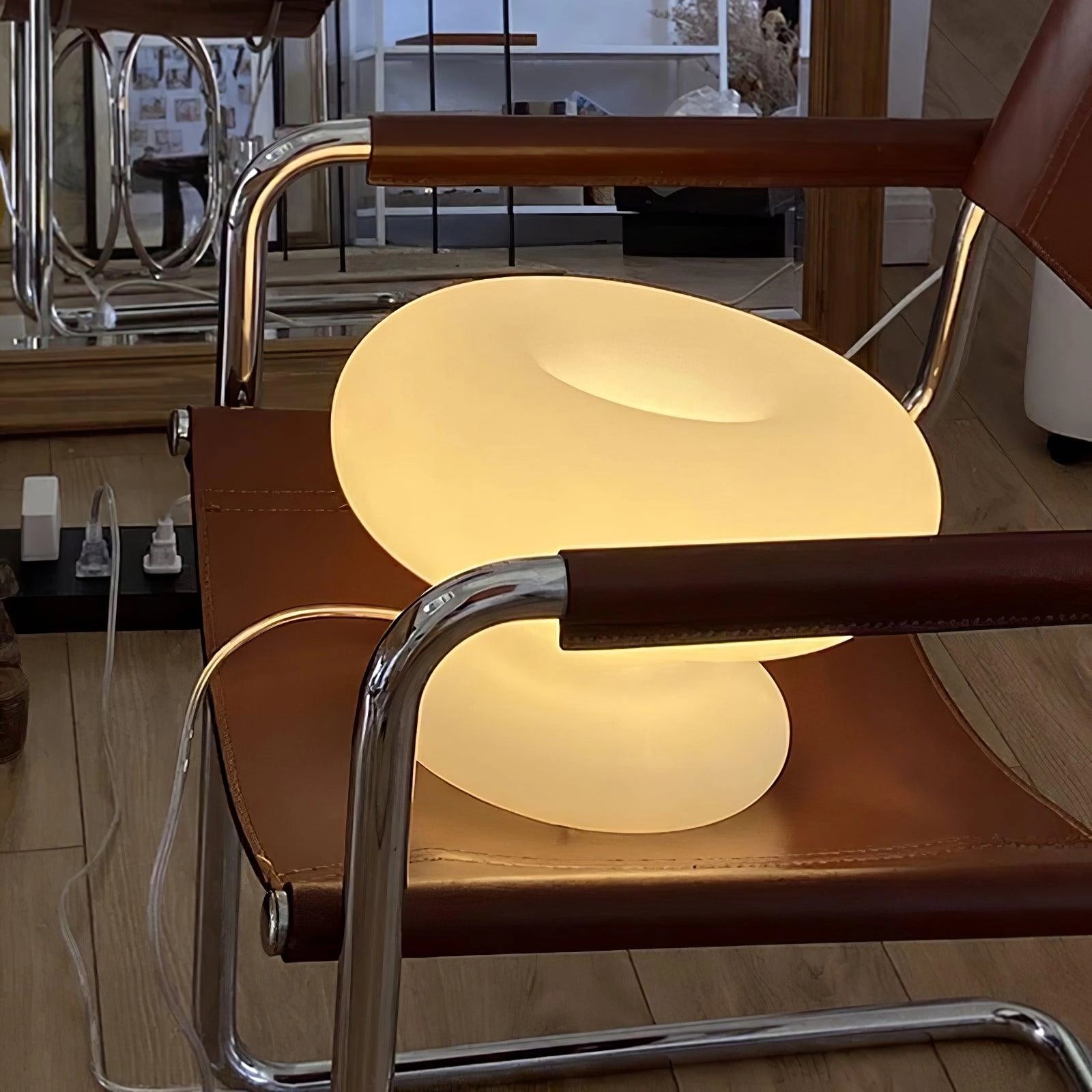 A minimalist modern mushroom table lamp with a wooden base, placed on a bedside table in a stylishly designed interior.