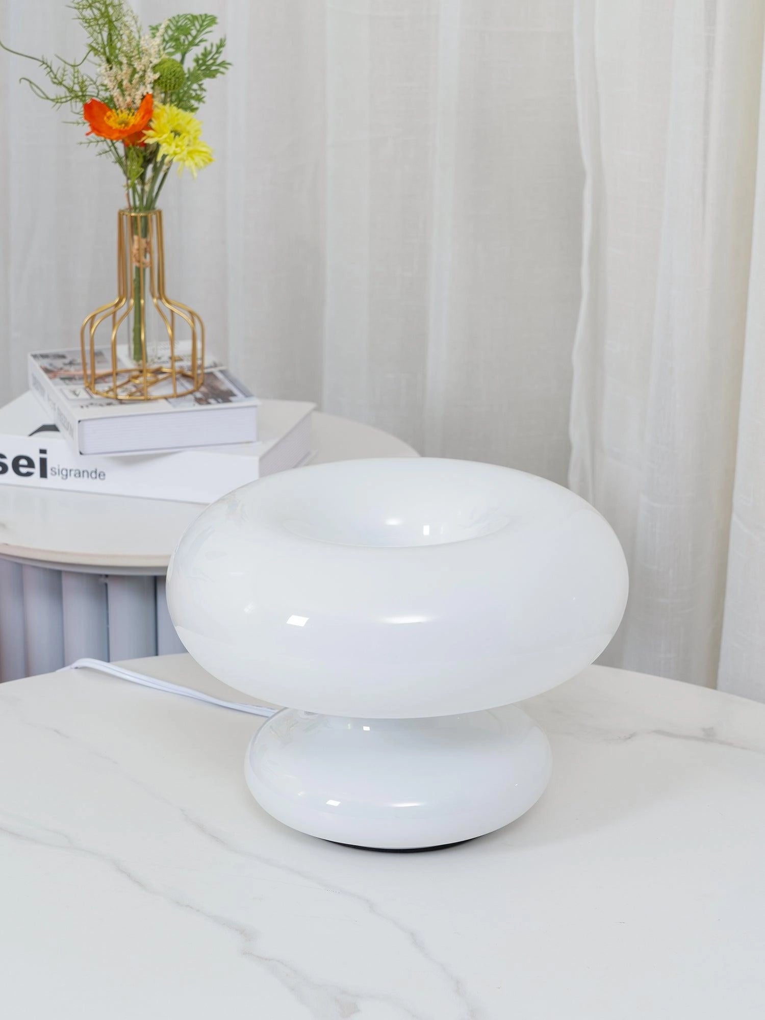 Modern Mushroom Table Lamp with a minimalist design on a wooden table, surrounded by ceramic dishware and a small flower arrangement.