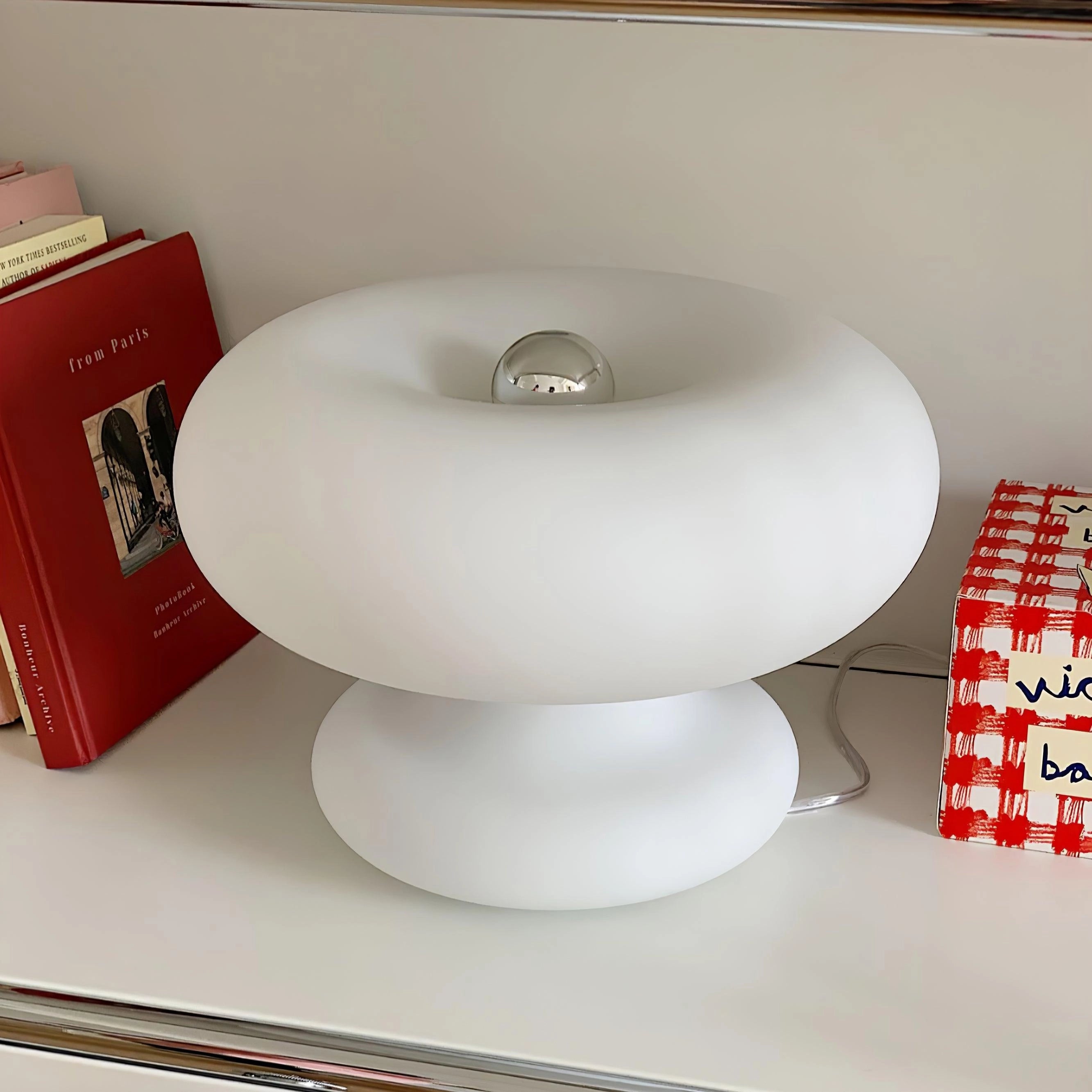 Modern mushroom-shaped table lamp with a minimalist design, ideal for bedside use. The lamp features a smooth, rounded plastic surface and emits a soft, warm light, perfect for a contemporary home setting.