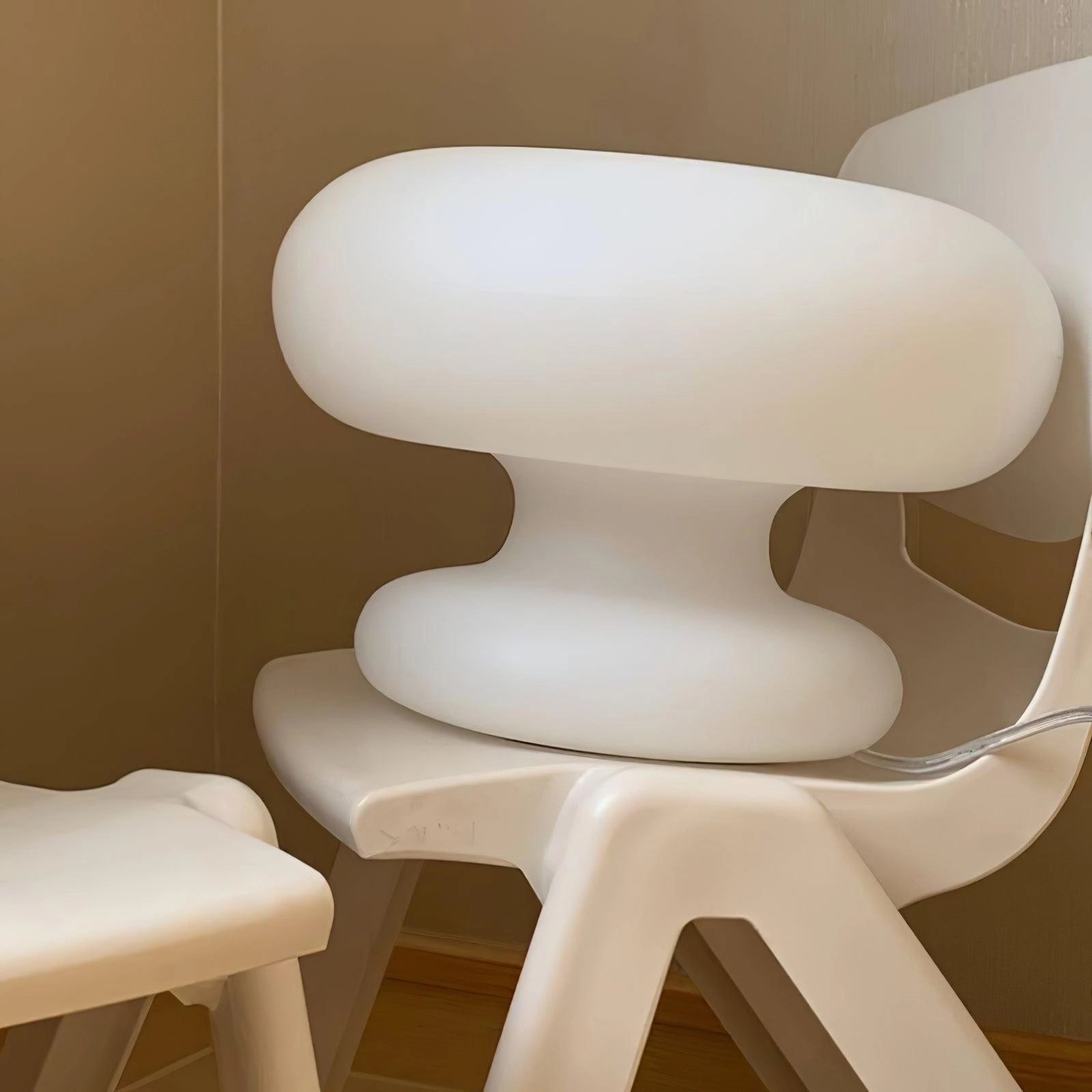 Modern mushroom-shaped table lamp with a minimalist design, placed on a bedside table, featuring a wooden base and sleek lighting accessory, enhancing the comfort and aesthetics of the room's interior design.