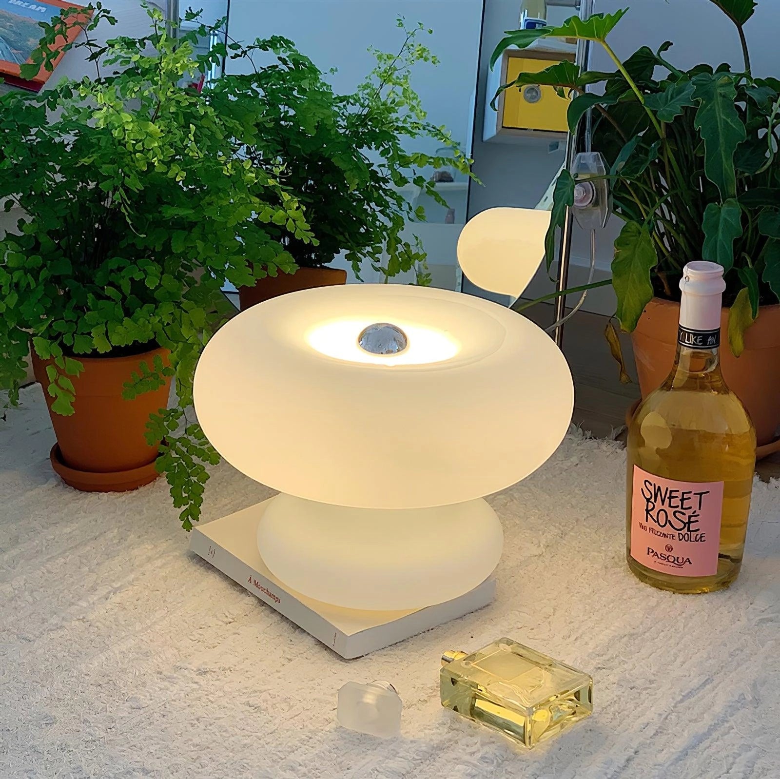 Modern Mushroom Table Lamp with minimalist design, placed on a wooden bedside table next to a small plant in a flowerpot.