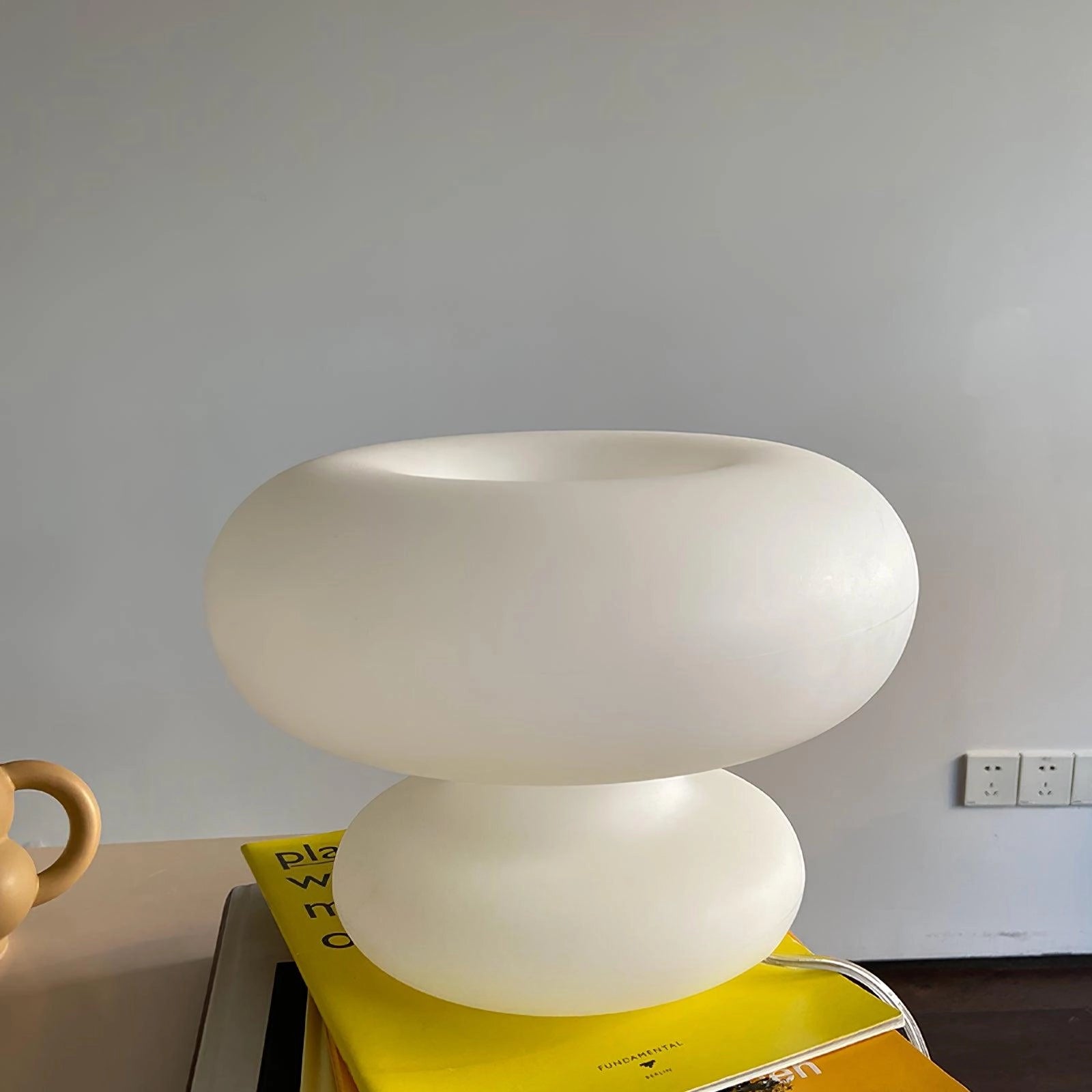 Modern mushroom-shaped table lamp featuring a minimalist design, ideal as a bedside light, with a smooth ceramic base and circular light fixture.