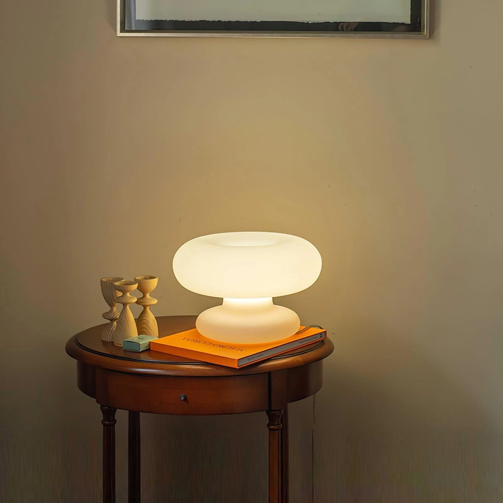 Modern Mushroom Table Lamp with minimalist design on a wooden table next to a picture frame and hardwood floor.