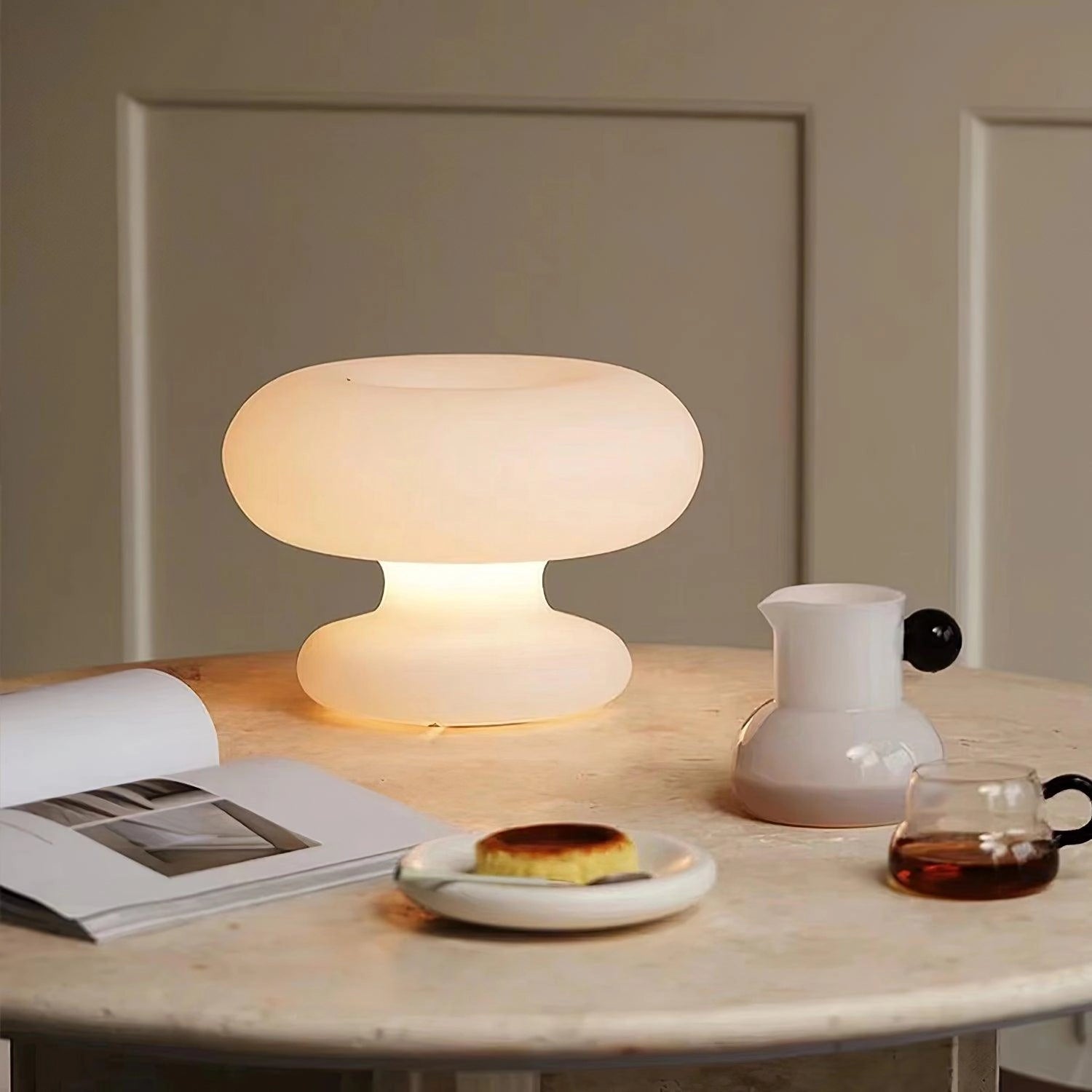 Minimalist Modern Mushroom Table Lamp on a wooden bedside table with contemporary tableware including a plate and cup, showcasing elegant interior design.