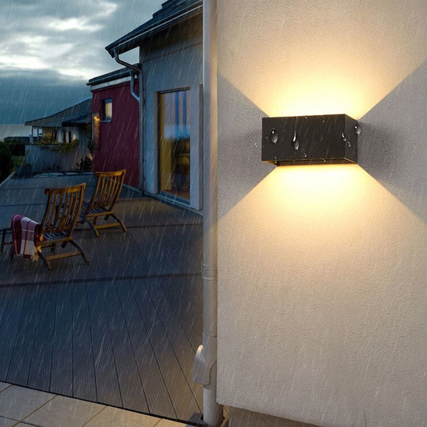 Modern rectangular LED outdoor wall light in black mounted on the exterior wall of a contemporary building, showcasing its sleek design against a backdrop of blue sky with scattered clouds.