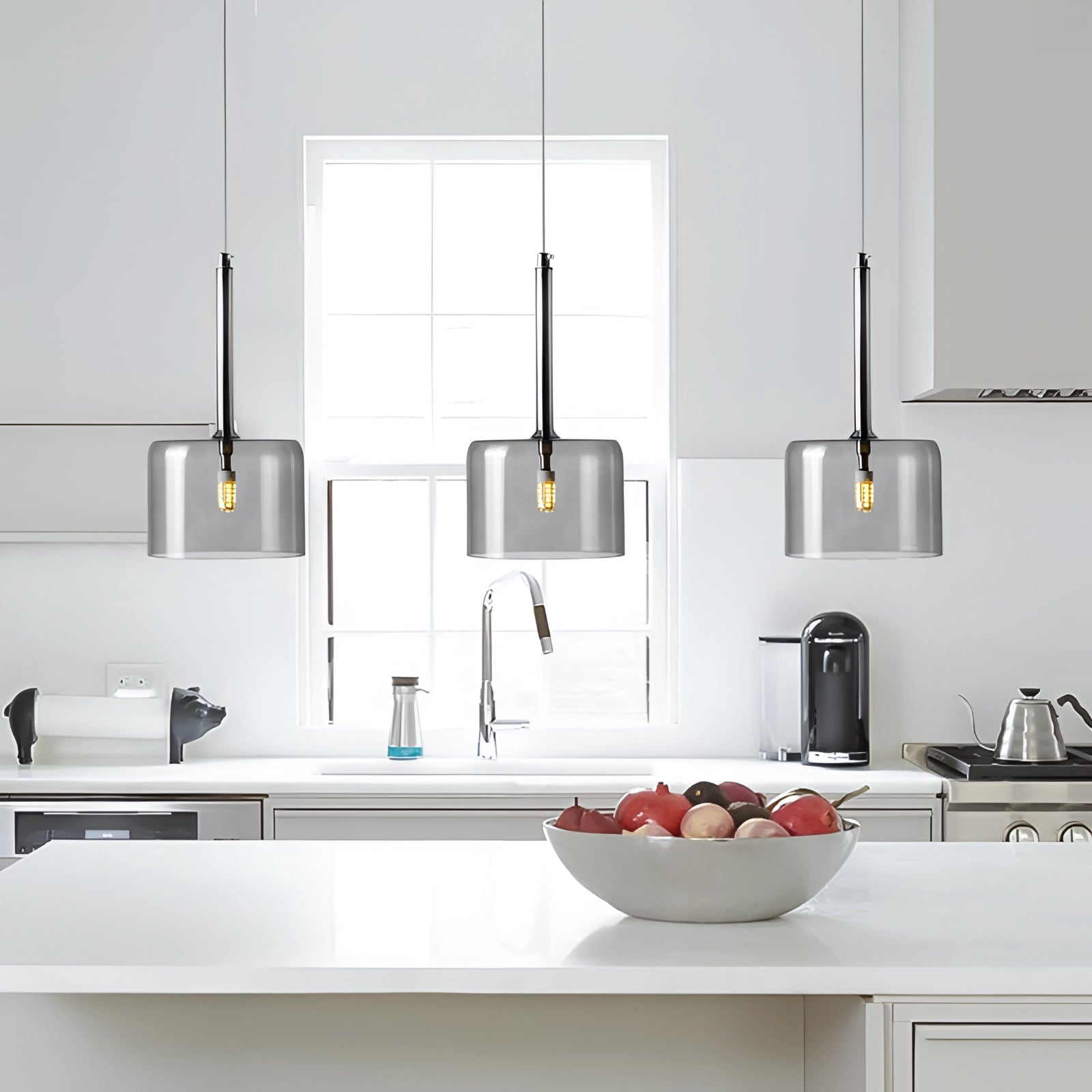 Modern Scandinavian glass pendant lights hanging from the ceiling in a stylish interior space with grey cabinetry, wood accents, and houseplants, highlighting the luxury design and cozy ambiance in a kitchen or living room setting.