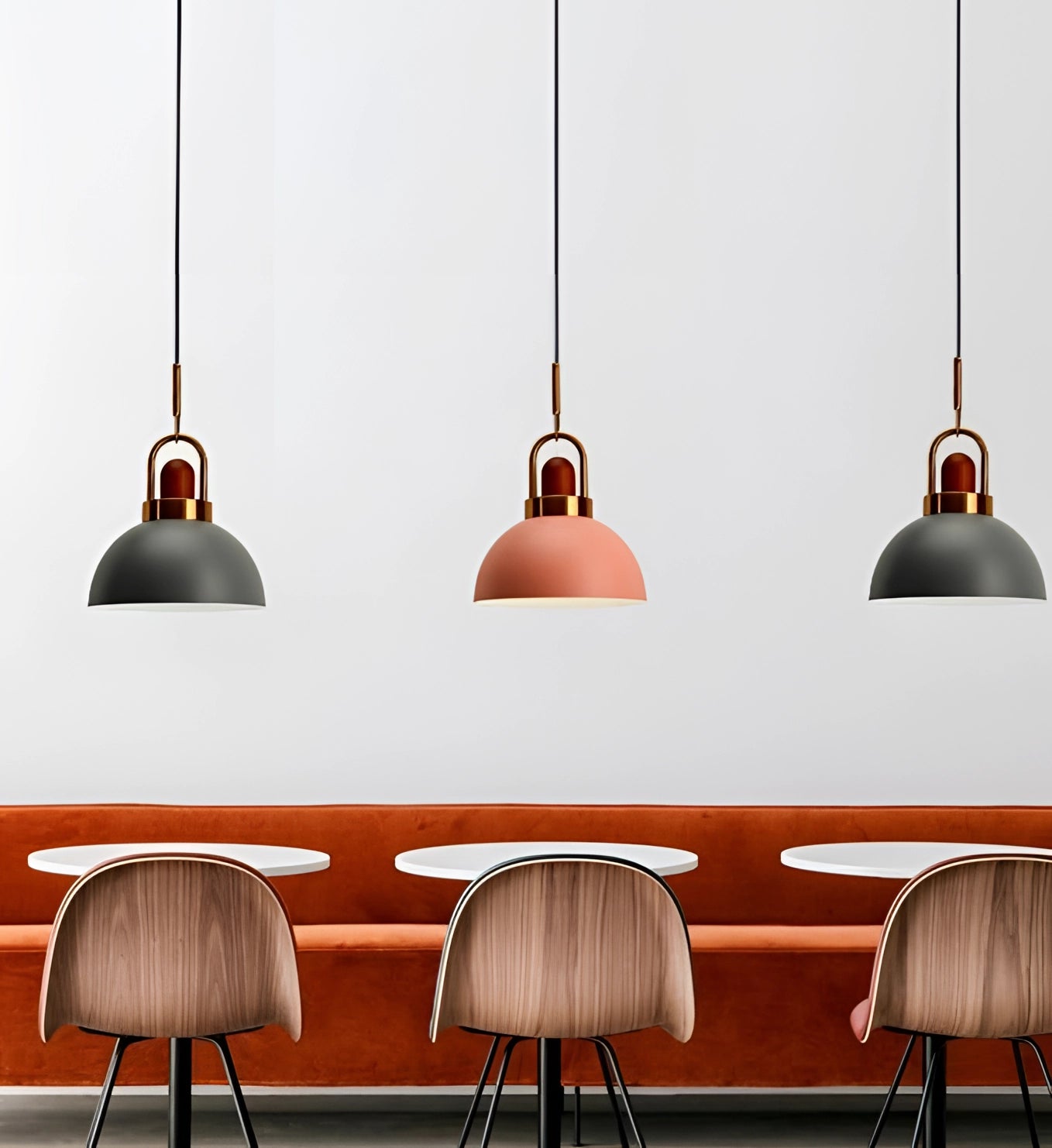 
A modern Scandinavian matte pendant light with a copper accent, hanging in an interior space. The light fixture exudes a warm glow, complementing the minimalistic design elements of the room. The surrounding decor features a blend of white and wood tones, enhancing the contemporary atmosphere.