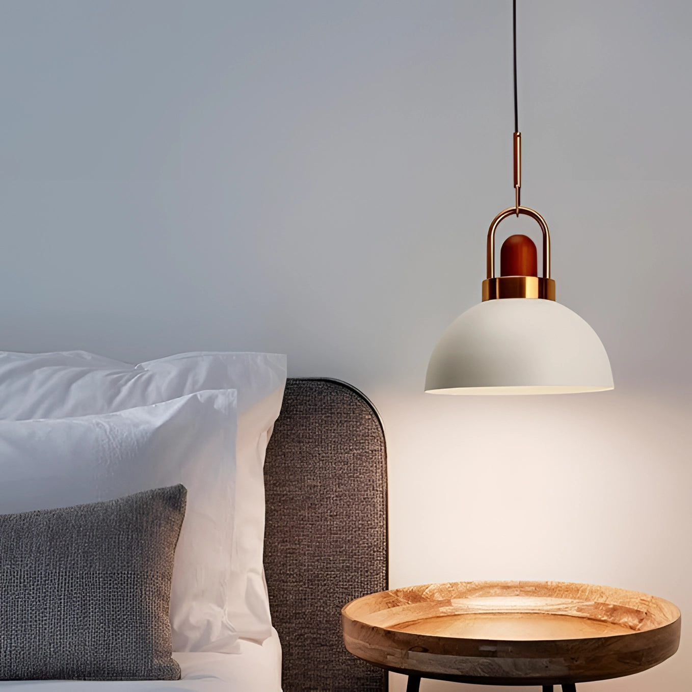 Modern Scandinavian matte pendant light with copper accents hanging above a wooden table set with dishware and serveware, creating a warm and inviting atmosphere.