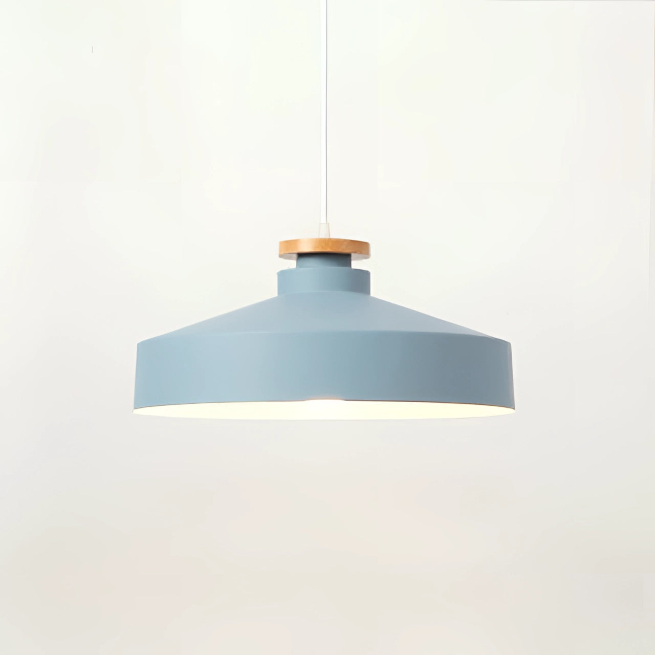 Modern Scandinavian pendant light with a blue disk-shaped lampshade, wooden accents, and adjustable height, mounted on a ceiling.