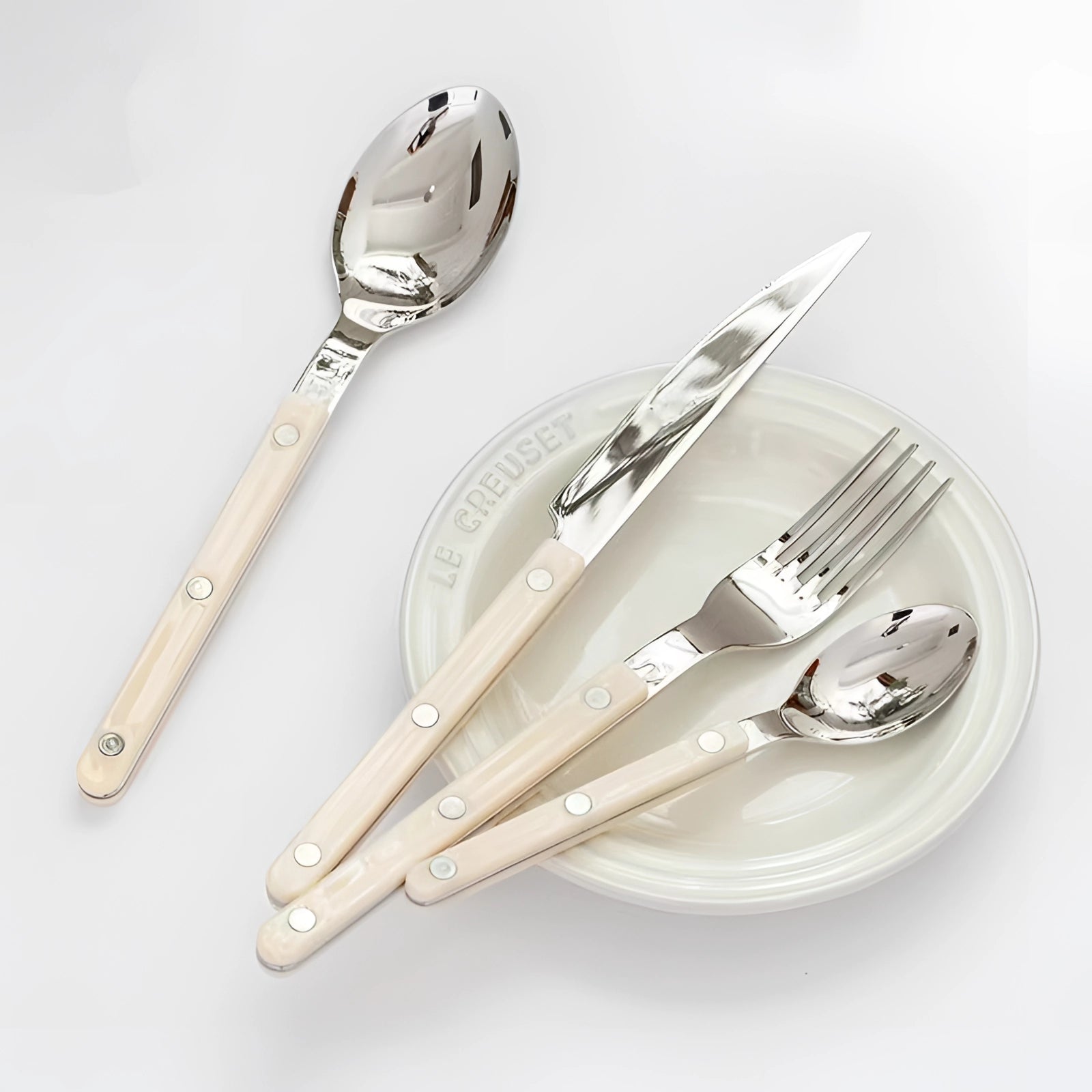 Modern stainless steel cutlery set with 24 pieces, featuring sleek black handles, elegantly arranged on a table.