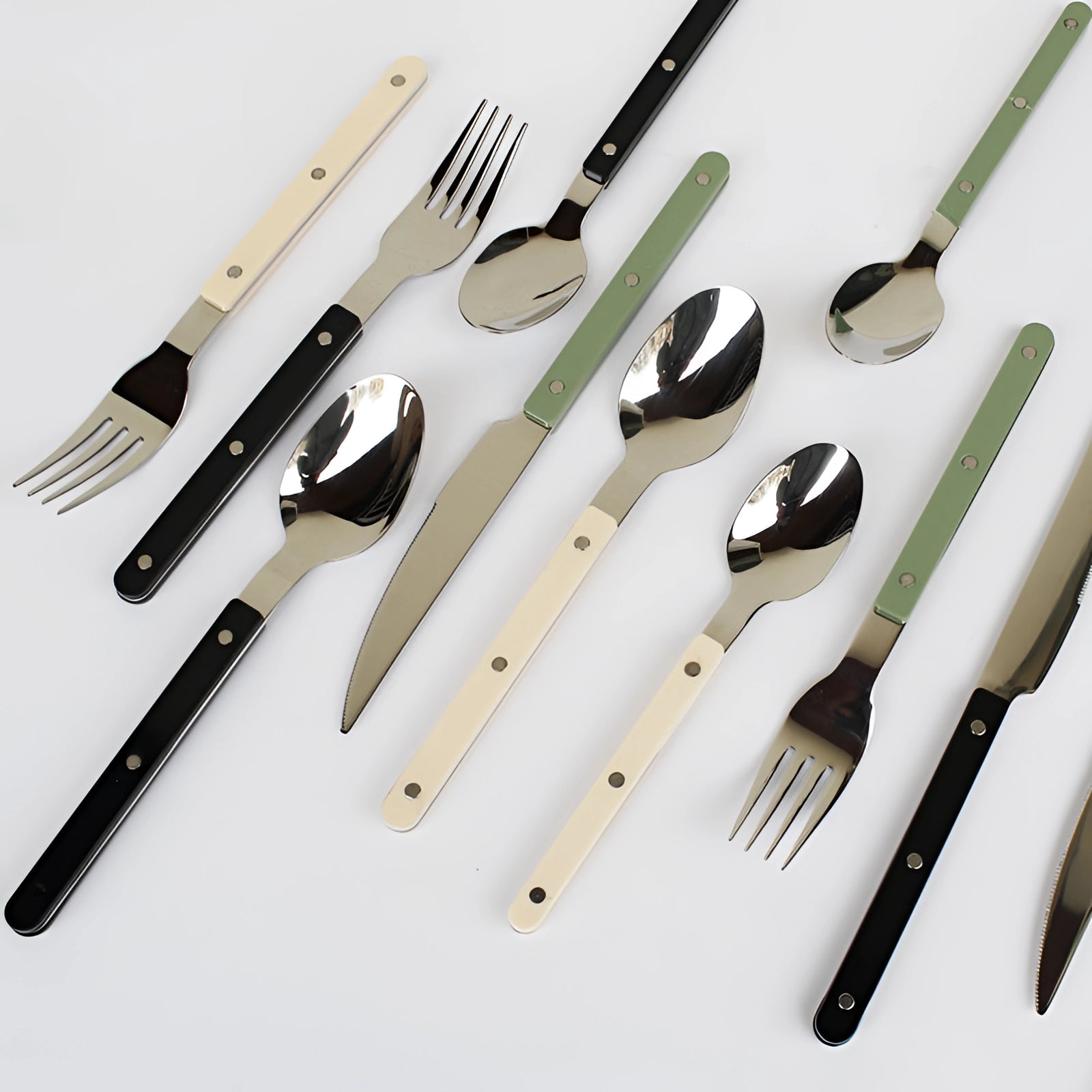 Modern stainless steel cutlery set with black handles, consisting of 24 pieces, including forks, knives, and spoons, displayed on a wooden surface.