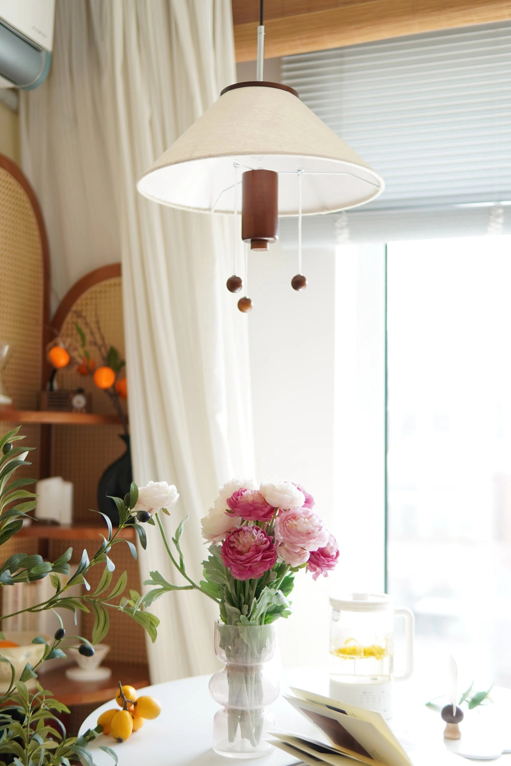 Modern triangle pendant lamp with wooden accents, adjustable lighting, hanging above a stylish interior design setting with an orange vase of flowers.