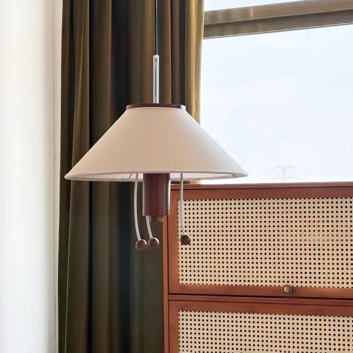 Modern triangle pendant lamp with wooden accents hanging from ceiling, providing adjustable lighting in a room with large windows and hardwood floor.