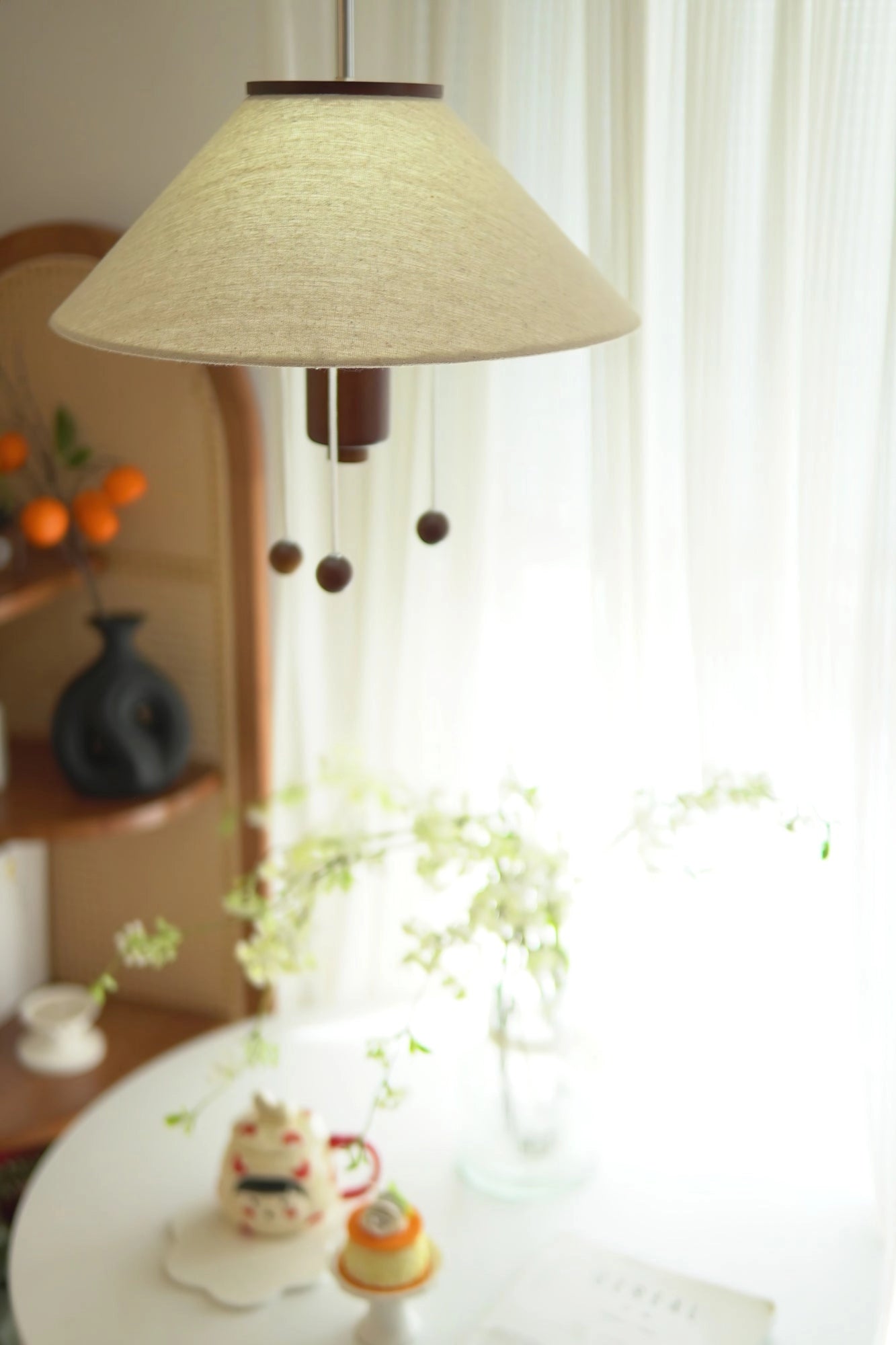 Modern Triangle Pendant Lamp with Wooden Accents hanging above a dining table set with tableware, drinkware, and a plant by a window.