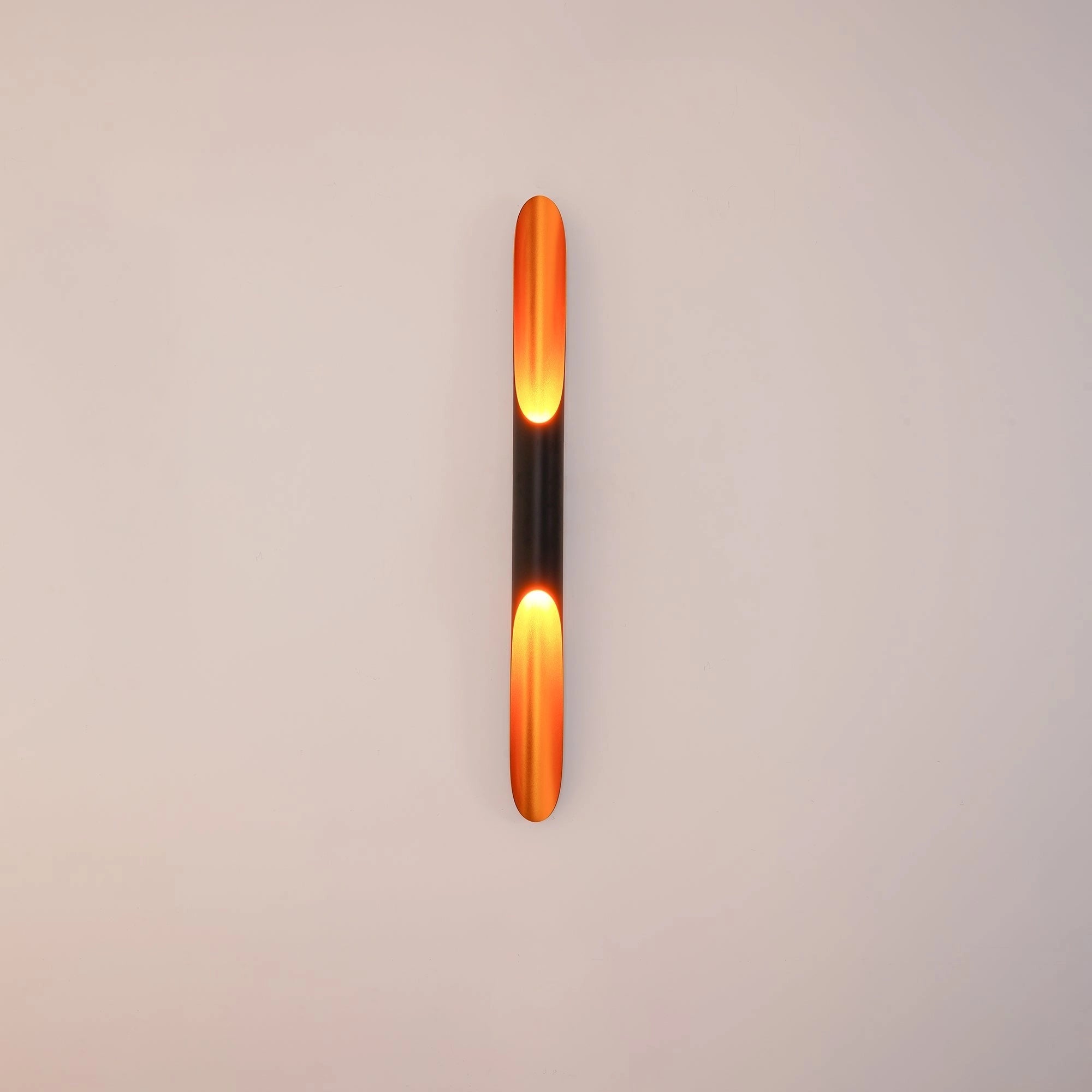 Modern vertical LED wall sconce with a minimalist architectural design, featuring a cylindrical shape and an amber-tinted glow.