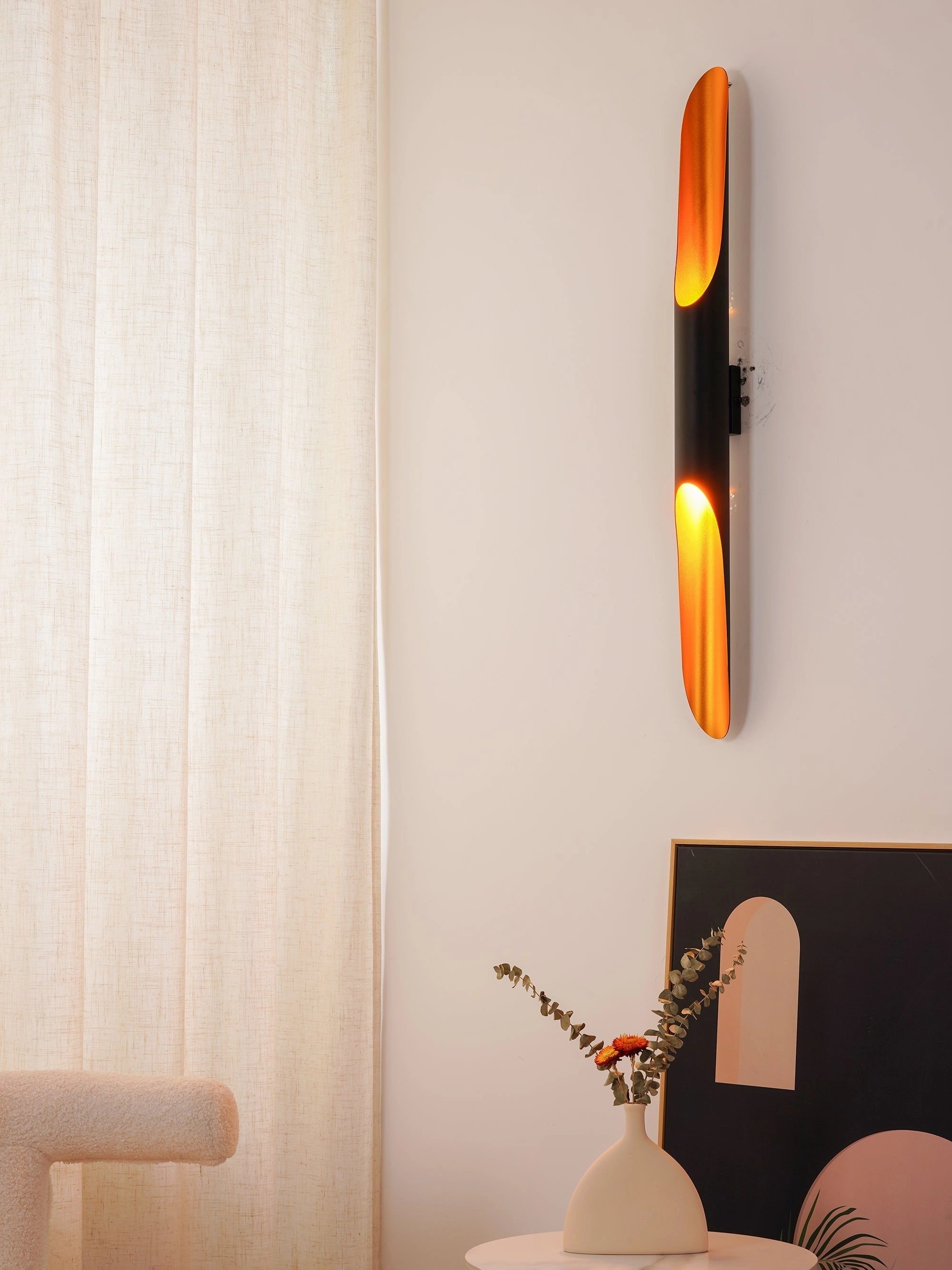 Modern vertical LED wall sconce with a minimalist architectural design, mounted on a wooden wall in a contemporary interior setting, showcasing a warm orange glow that adds artistic ambiance to the room.