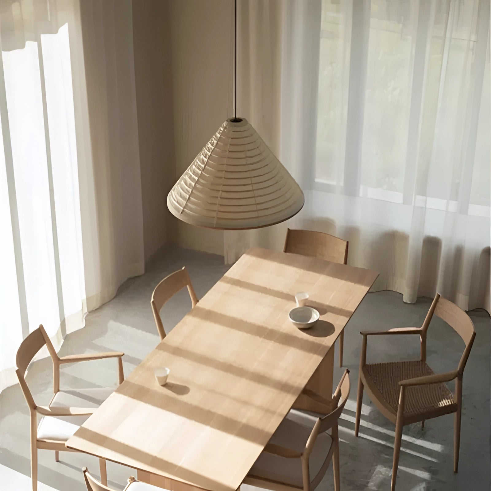 Modern white Scandinavian cone pendant light with minimalist design hanging above a wooden table and chairs in a well-lit room with windows and curtains, highlighting the interior design elements.