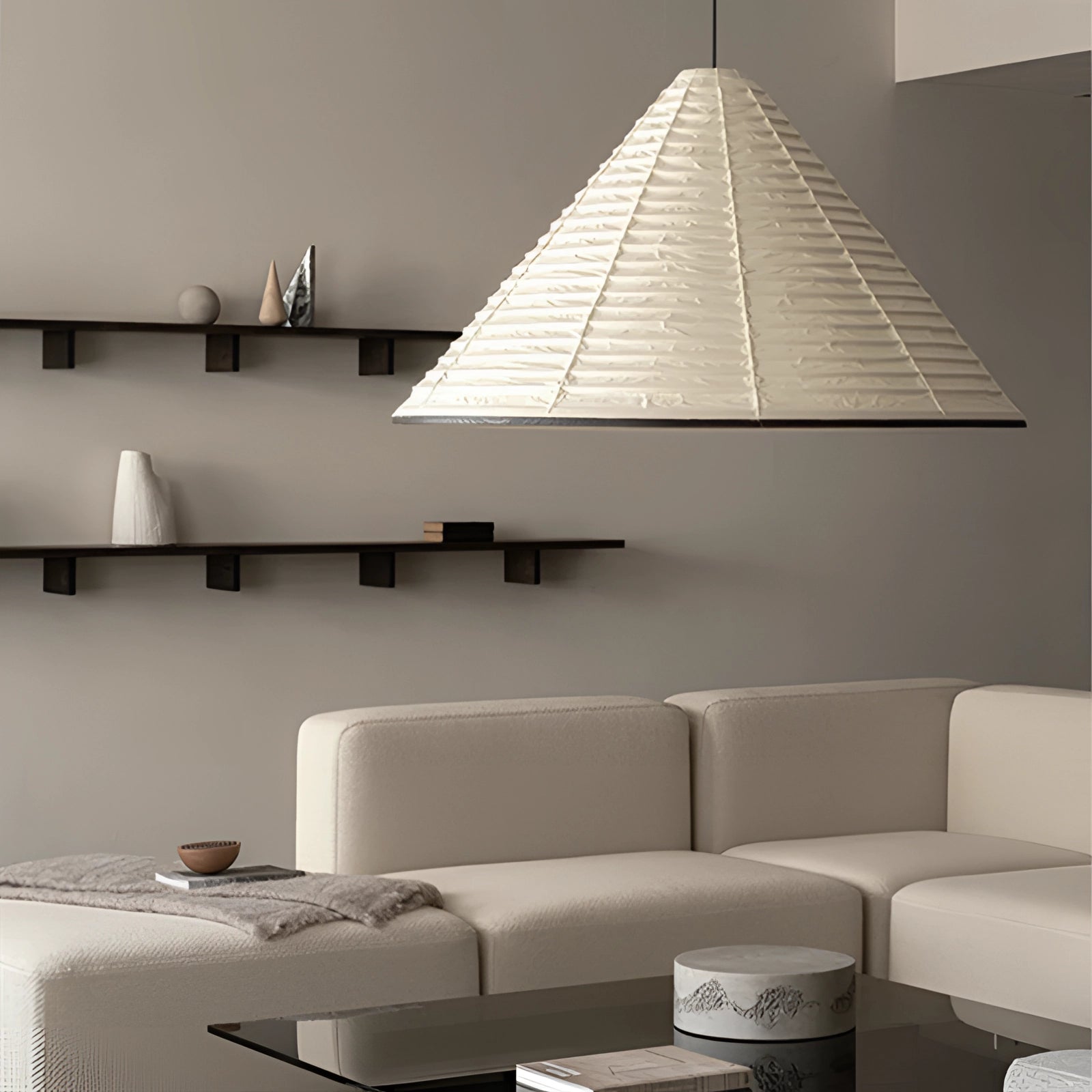 Modern white Scandinavian cone pendant light with minimalist design, featuring a sleek shade hanging from the ceiling, illuminating a contemporary interior space. The light is positioned above a grey couch with wooden elements in the room, contributing to the overall architectural aesthetics.