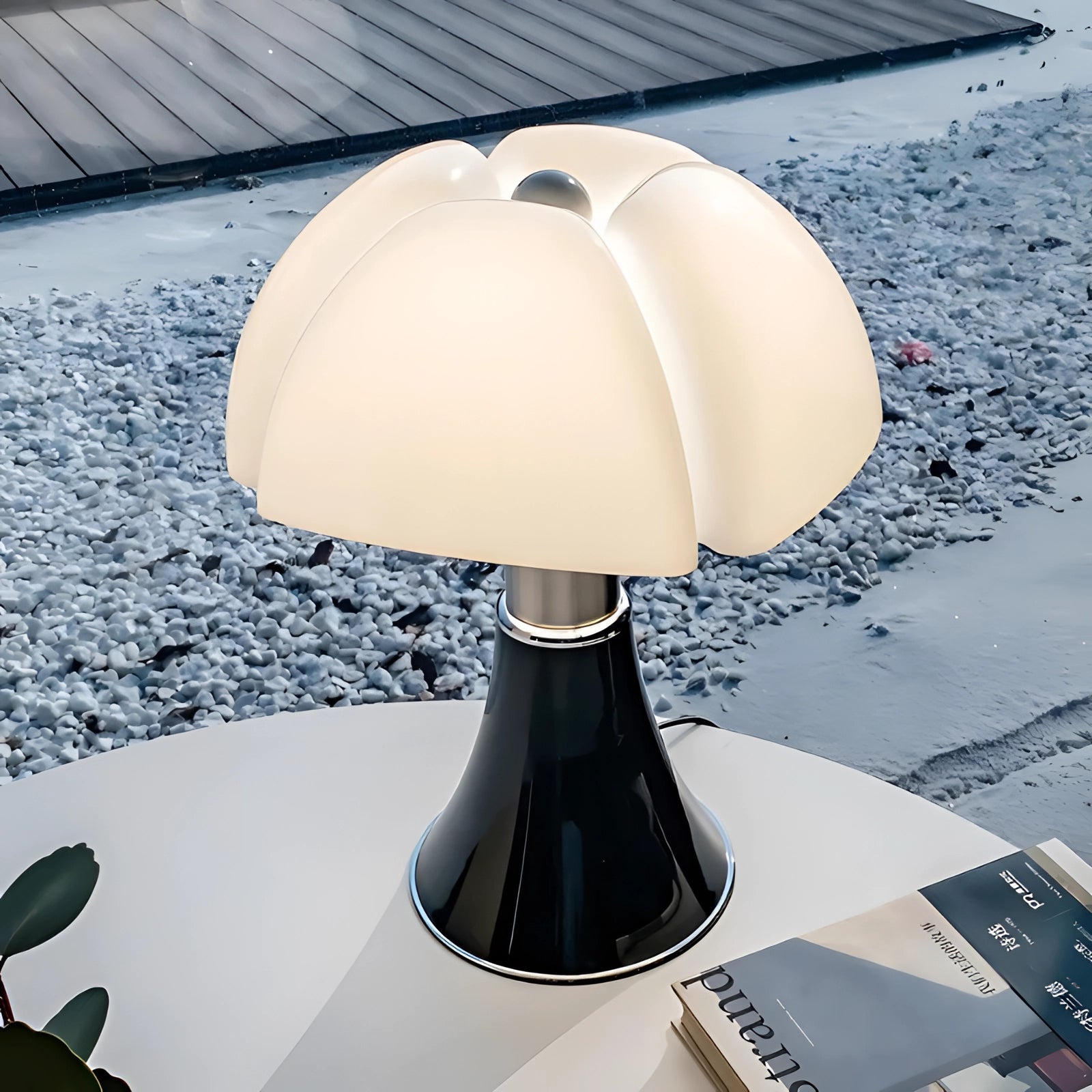 Modern white table lamp with a contemporary minimalist design resembling a mushroom, featuring a smooth, sleek surface and metal accents, illuminated in a softly lit setting.