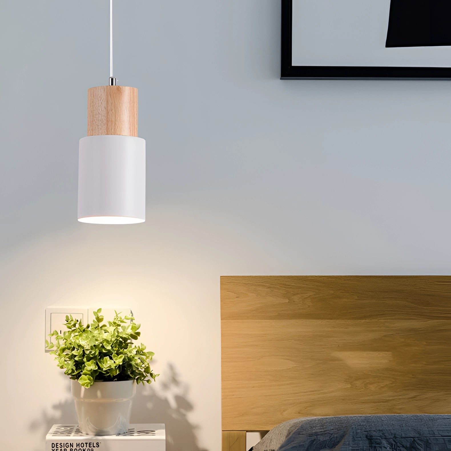 Nordic Modern Pendant Light with a Scandinavian style featuring wood accents hanging in a stylish interior setting; the light casts a warm orange glow against a grey wall, enhancing the comfort and modern design of the space. A plant is visible in the background, contributing to the aesthetic.