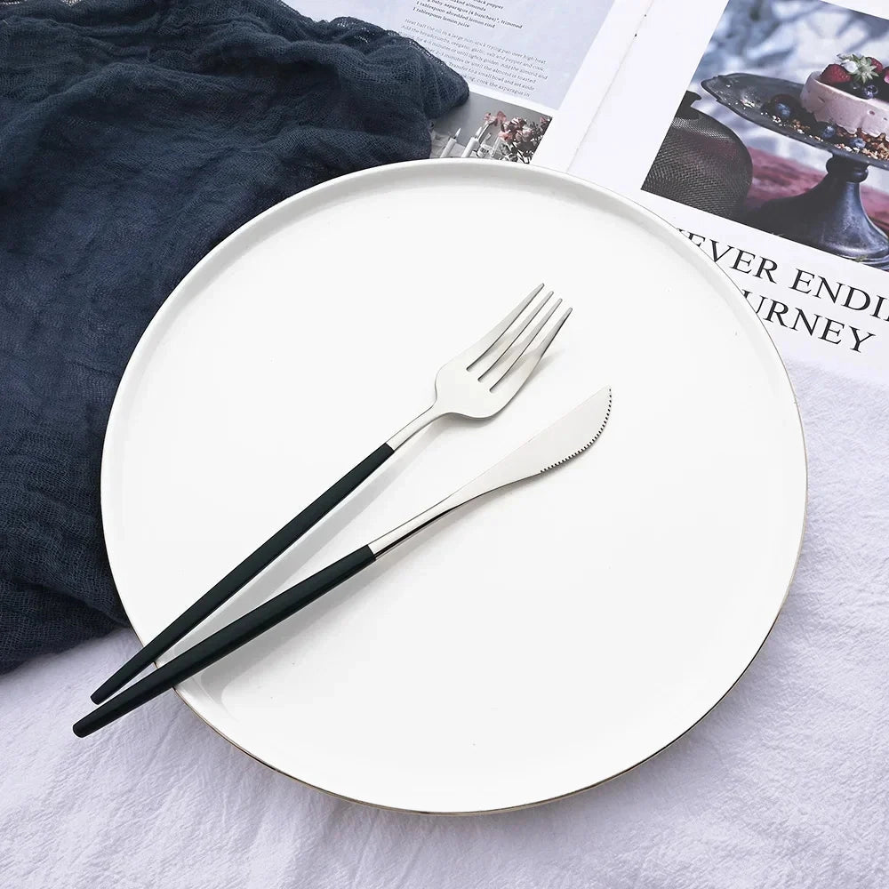 Elegant modern pink stainless steel flatware set displayed on a grey tablecloth, featuring a fork and other cutlery pieces arranged alongside a plate.