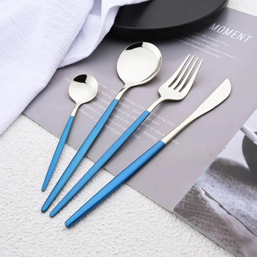 Elegant modern pink flatware set made of stainless steel, including a fork and table knife, displayed alongside a plate on a table with linens.