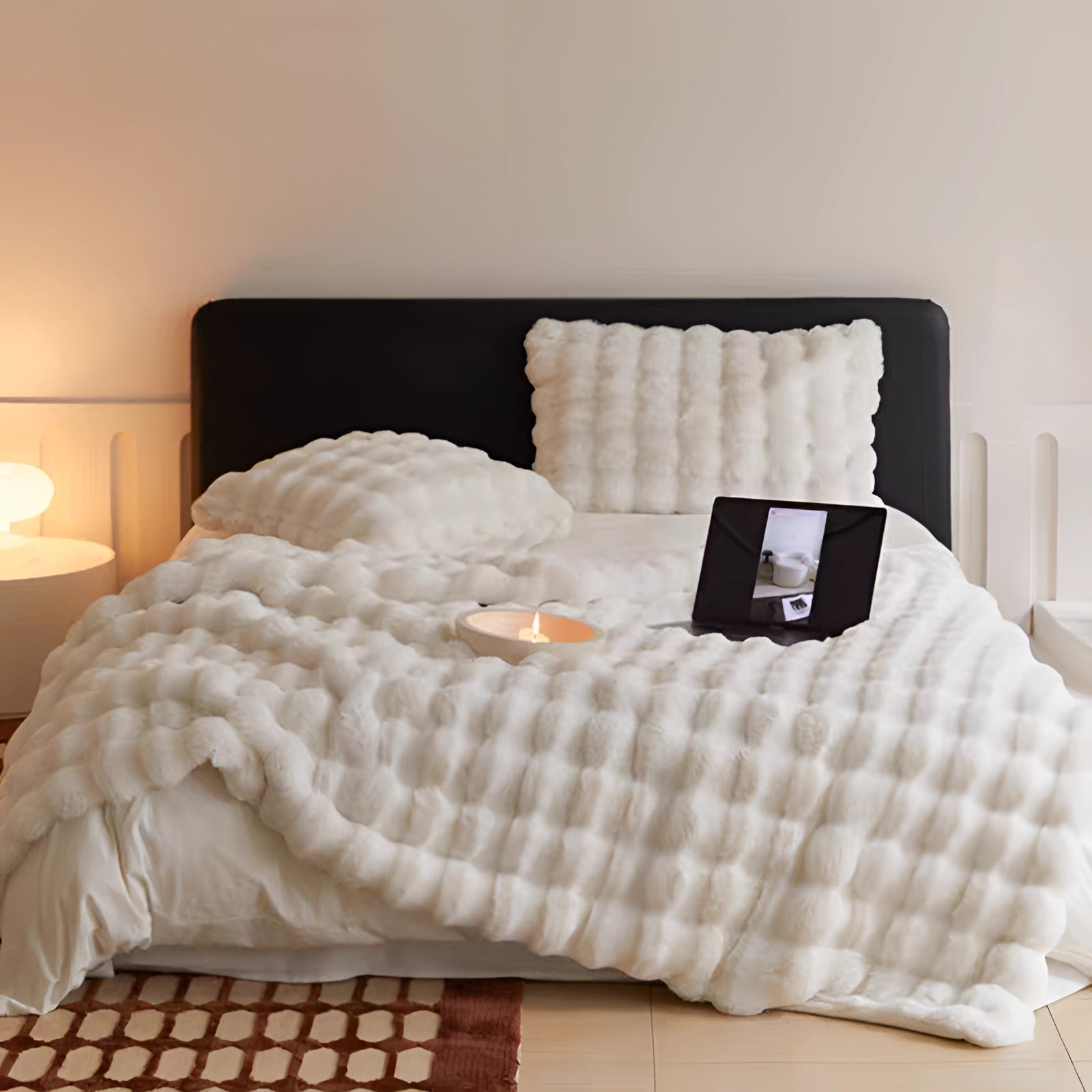 Plush pink chunky knit blanket draped over a bed in a cozy, well-lit bedroom setting with wooden furniture and a stylish lamp.