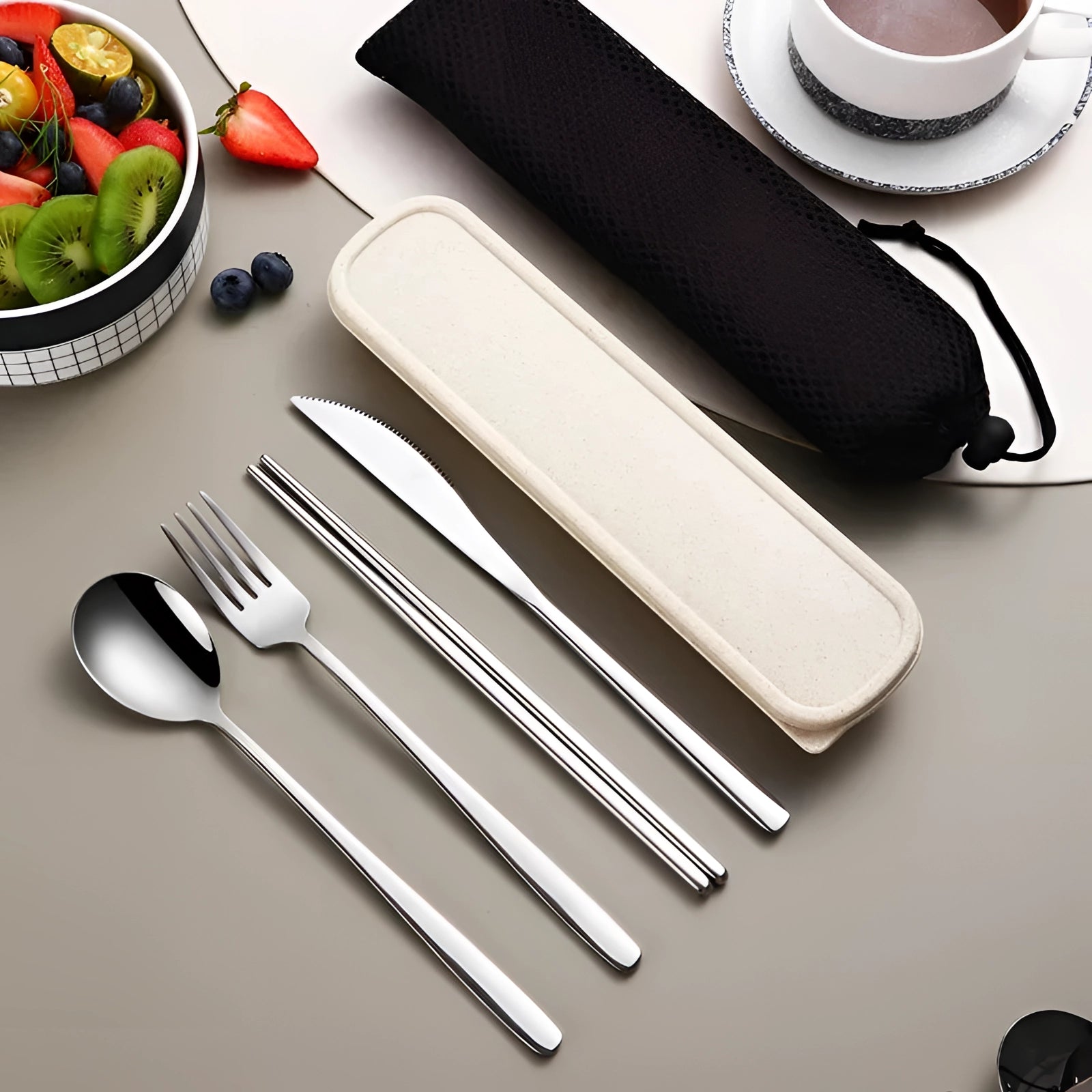 Portable eco-friendly stainless steel travel cutlery set in silver, displayed with a fork and other utensils, neatly arranged on a rectangular plate or surface, illustrating its compact design and suitability for travel or use as tableware.